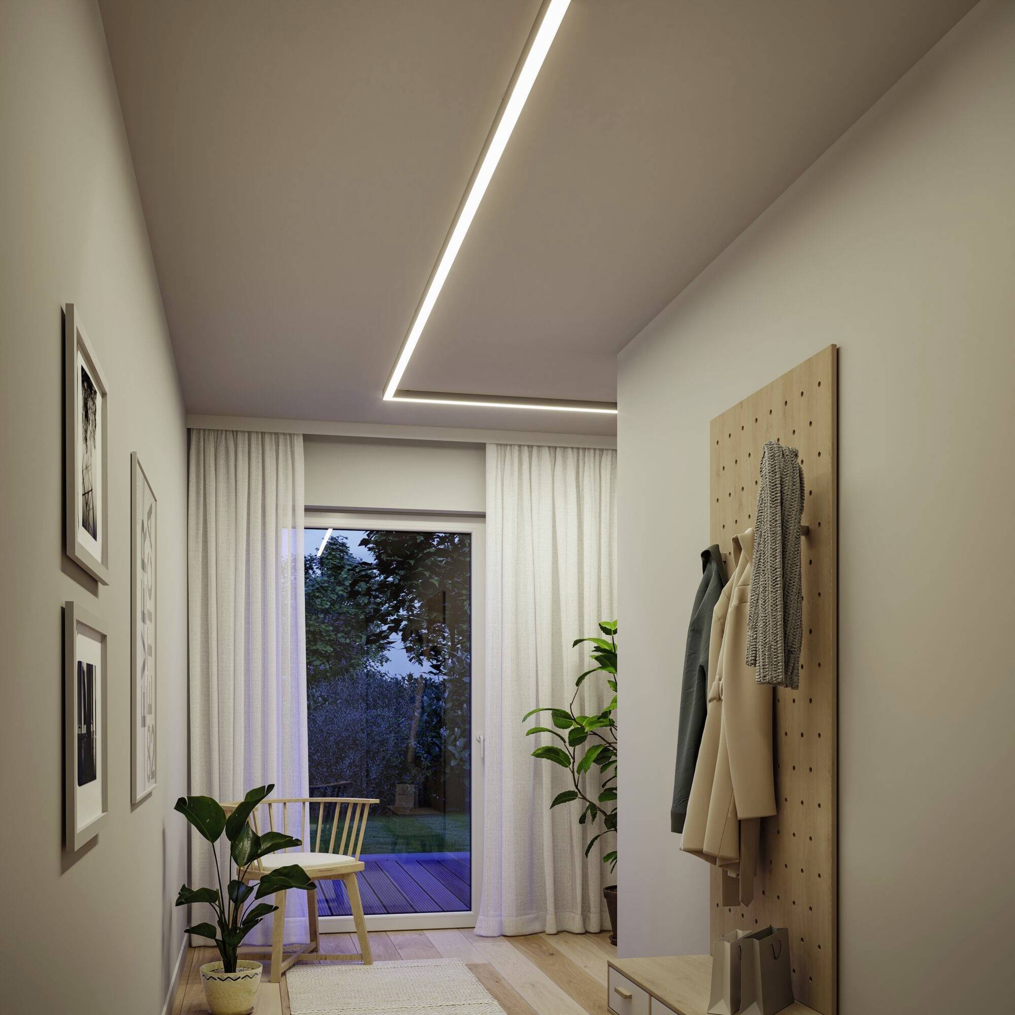 Ein Flur mit weißem Vorhang öffnet sich zu einem Balkon. Pflanzen und Kunstwerke schmücken den Raum. Ein Mantel hängt an der Garderobe.