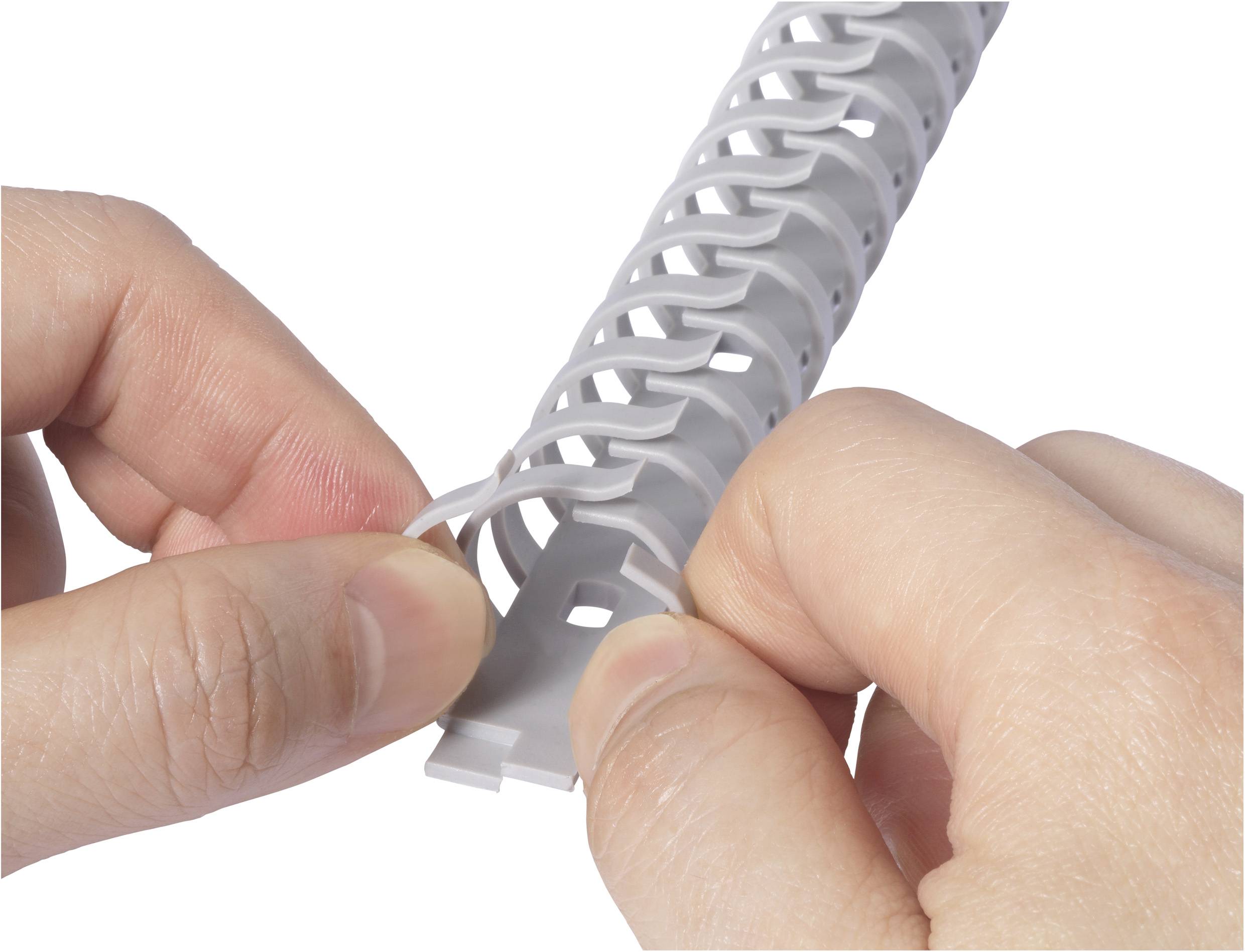 Person zieht weißen Plastik-Kabelschlauch auseinander, um darin Kabel zu organisieren. Nahaufnahme der Hände und des Kabelschlauchs.