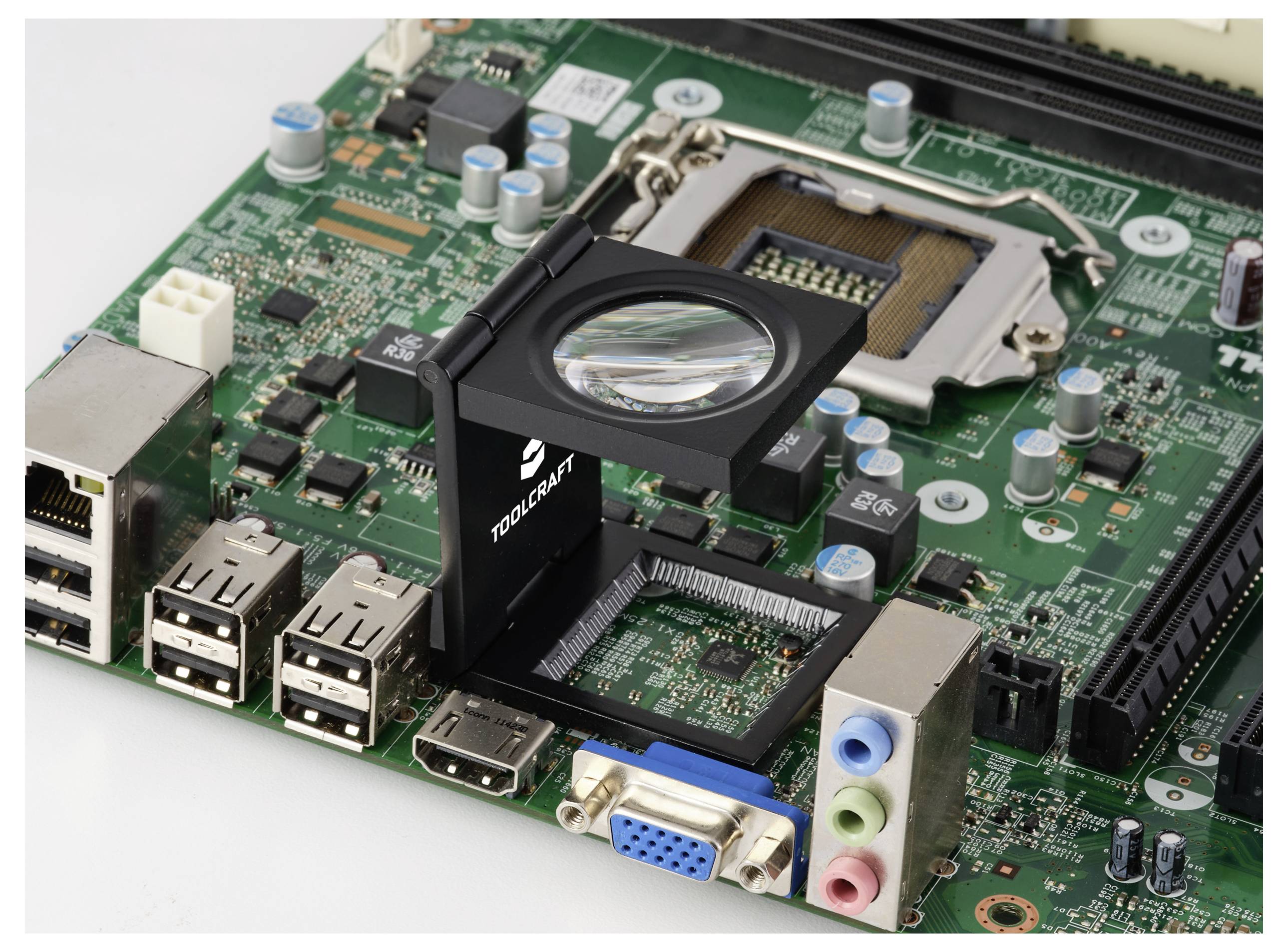 Eine Lupe ist auf einem Computerhauptboard platziert und hebt die komplexen Schaltkreisdetails und Anschlüsse hervor.