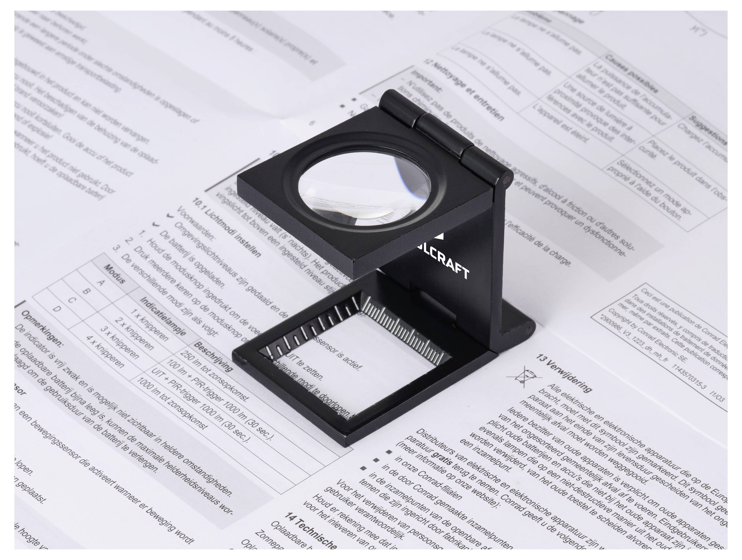 Eine Lupe mit einer Maßskala liegt auf einem technischen Dokument, das mit Tabellendaten und Text gefüllt ist und eine detaillierte Analyse andeutet.