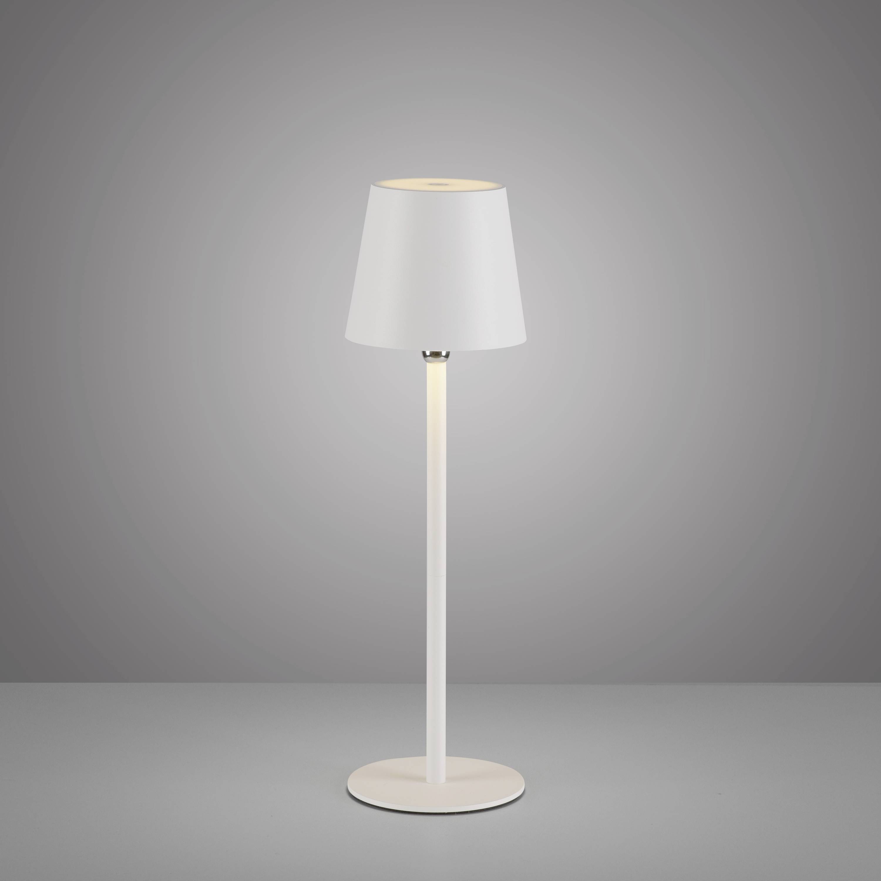 Weiße Tischlampe mit konischem Schirm steht auf grauer Oberfläche vor neutralem Hintergrund. Schlichtes, modernes Design.