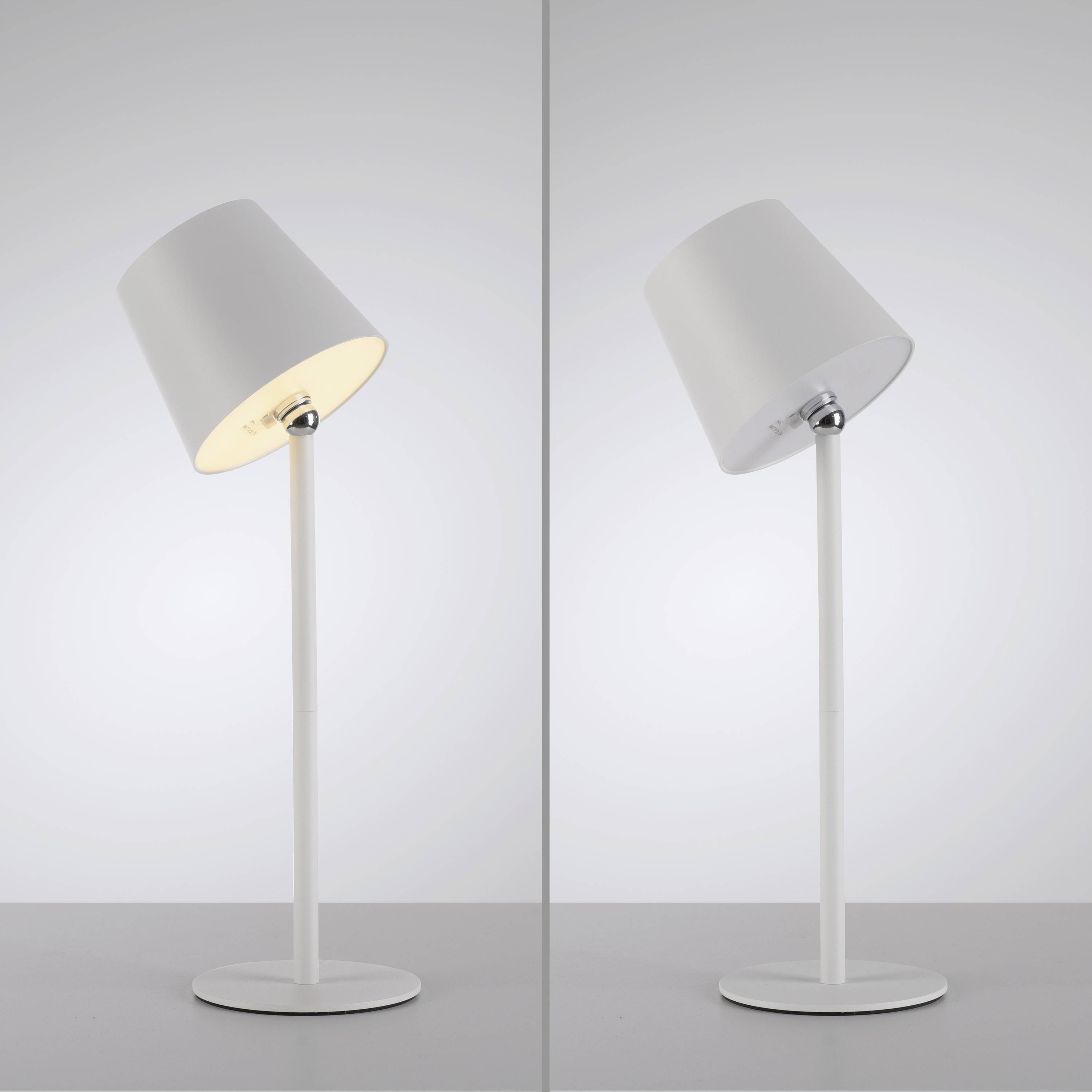 Zwei moderne Tischlampen, eine links leuchtend, die andere rechts ausgeschaltet. Beide haben einen schrägen weißen Lampenschirm.