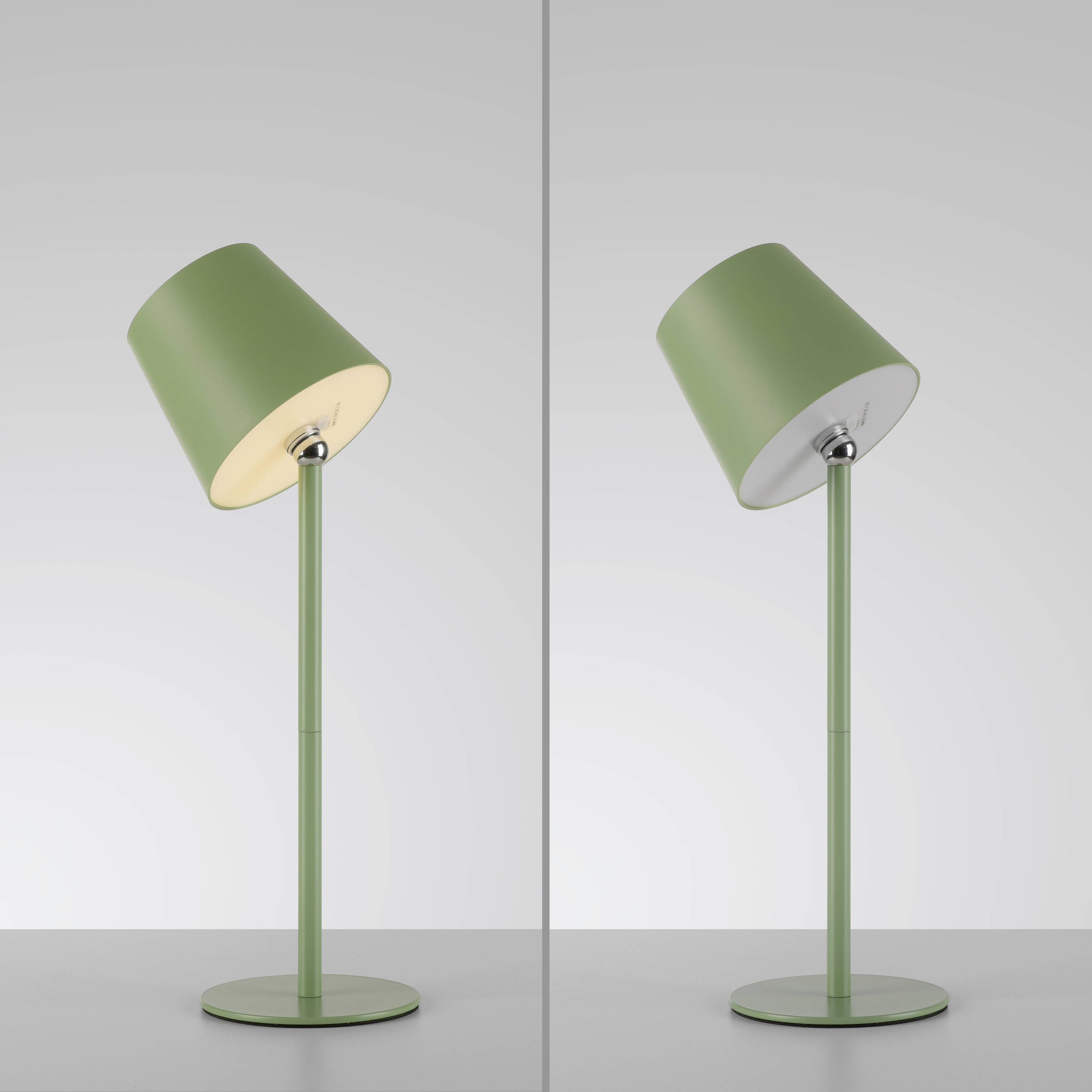 Zwei grüne Stehlampen, eine leuchtet, die andere ist ausgeschaltet. Beide haben einen schräg stehenden Lampenschirm und stehen auf einem Tisch.