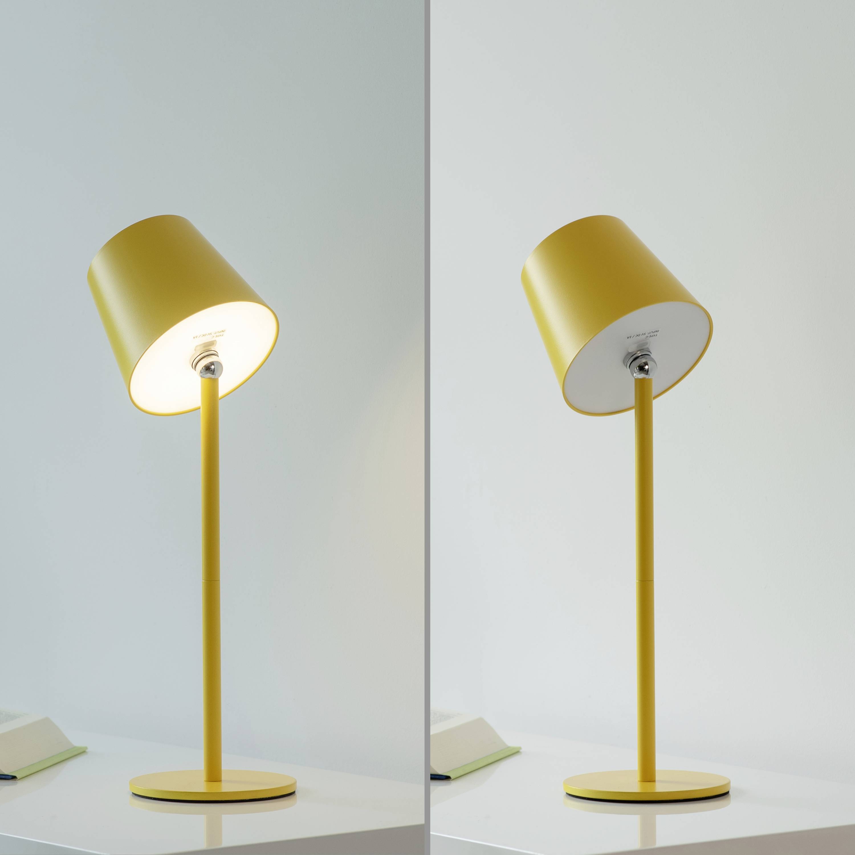 Zwei gelbe Tischlampen mit modernem Design auf einer weißen Oberfläche. Linke Lampe leuchtet, rechte Lampe ist ausgeschaltet.