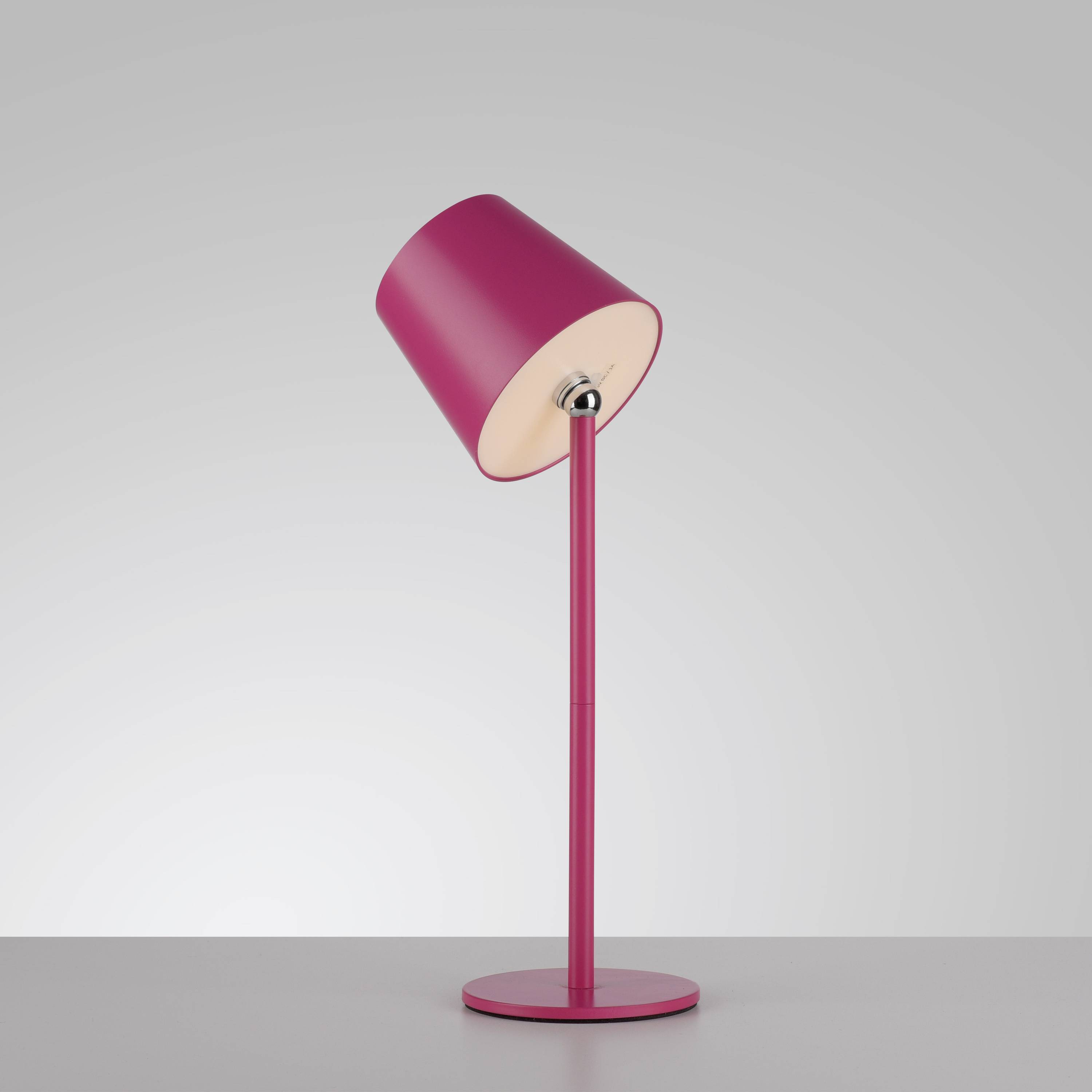 Moderne, pinke Tischlampe mit schrägem Lampenschirm auf grauem Hintergrund.