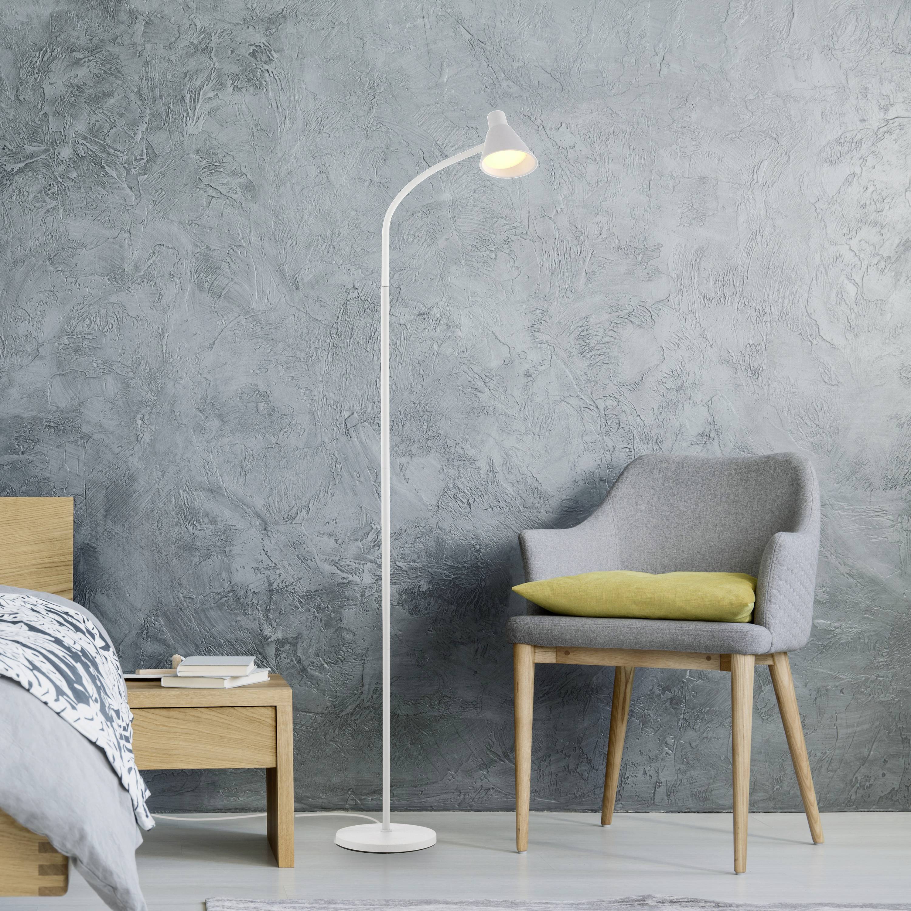 Graues Zimmer mit grauem Sessel, gelbem Kissen, Stehlampe und Holztisch mit Büchern und Wecker. Atmosphäre ruhig und modern.