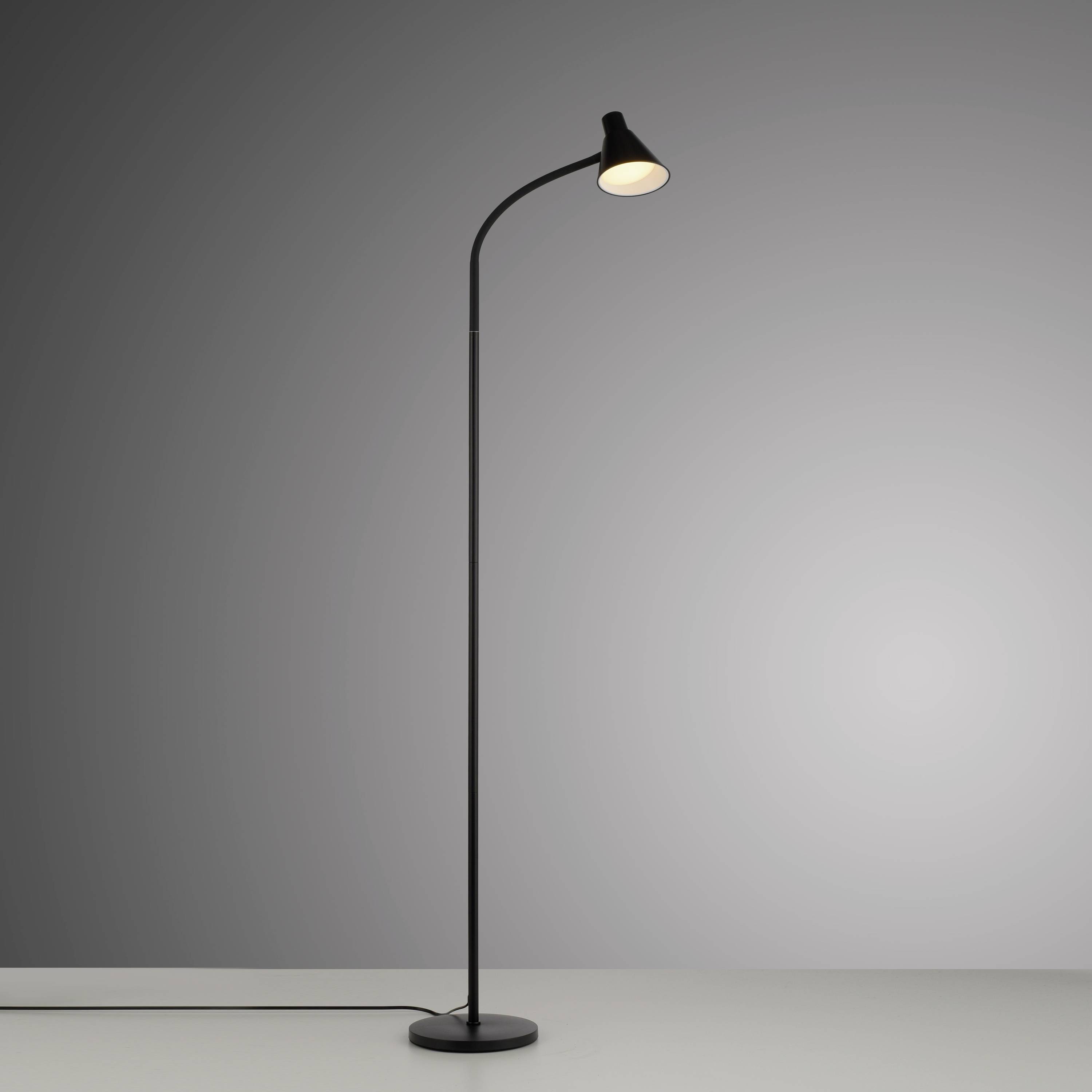 Eine moderne, schlanke Stehlampe mit gebogenem Hals, die warmes Licht ausstrahlt. Hintergrund ist neutral graue Wand.