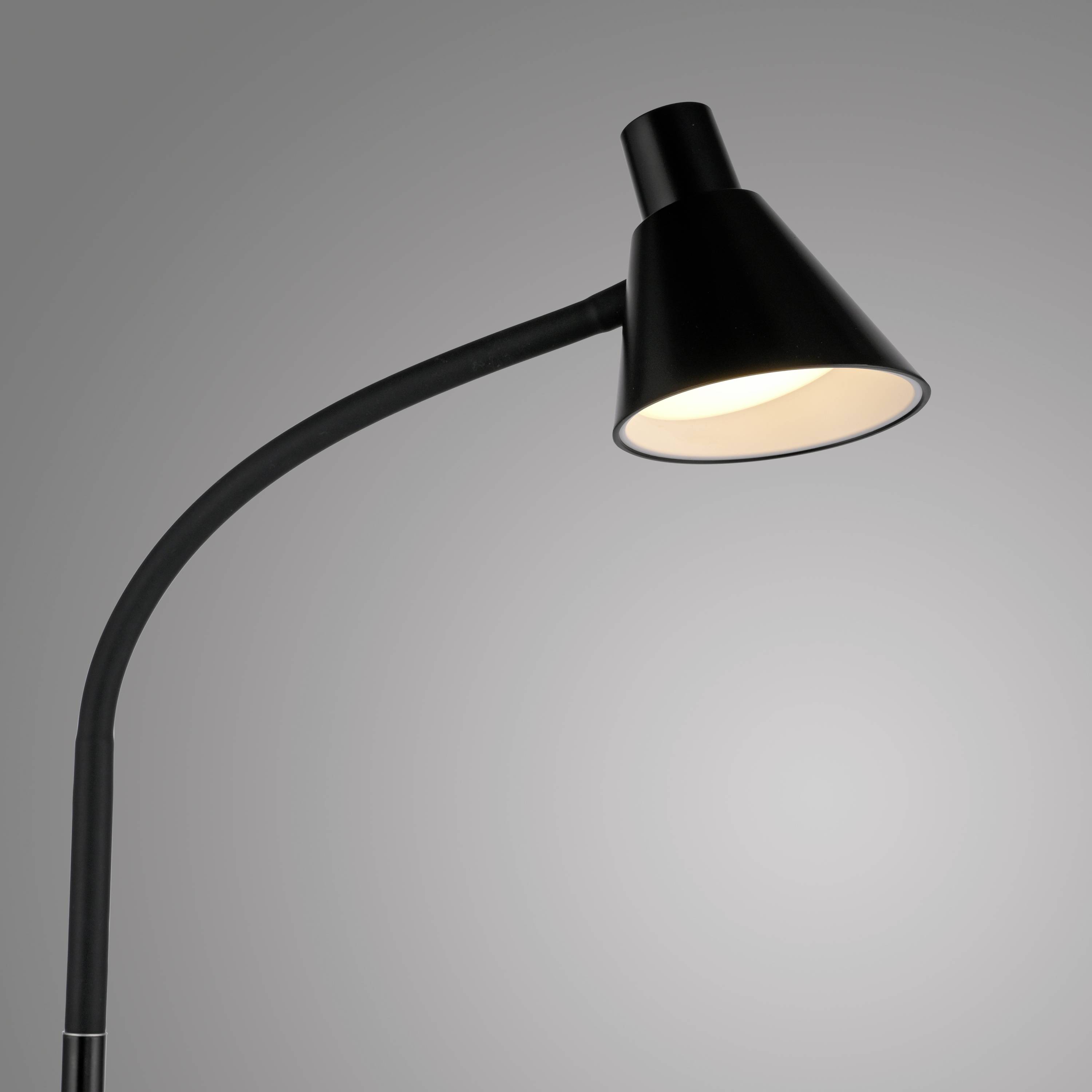 Eine schlanke, schwarze Stehlampe mit konischem Schirm leuchtet einen grauen Hintergrund aus. Moderne, minimalistische Gestaltung.