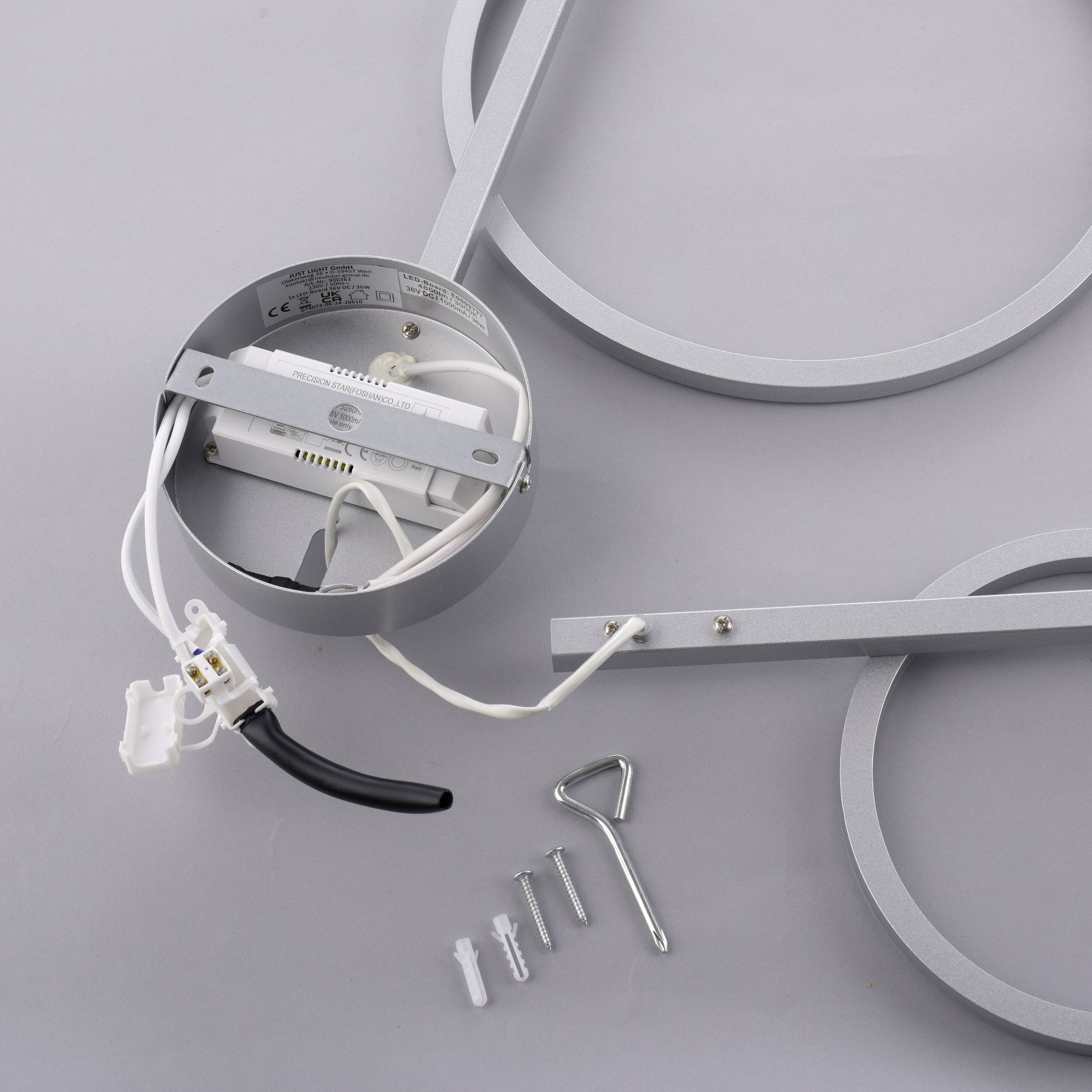 Silberne Deckenleuchte in Einzelteilen, bestehend aus runden LED-Rahmen mit sichtbarer Verkabelung und Montagematerial auf grauem Hintergrund.