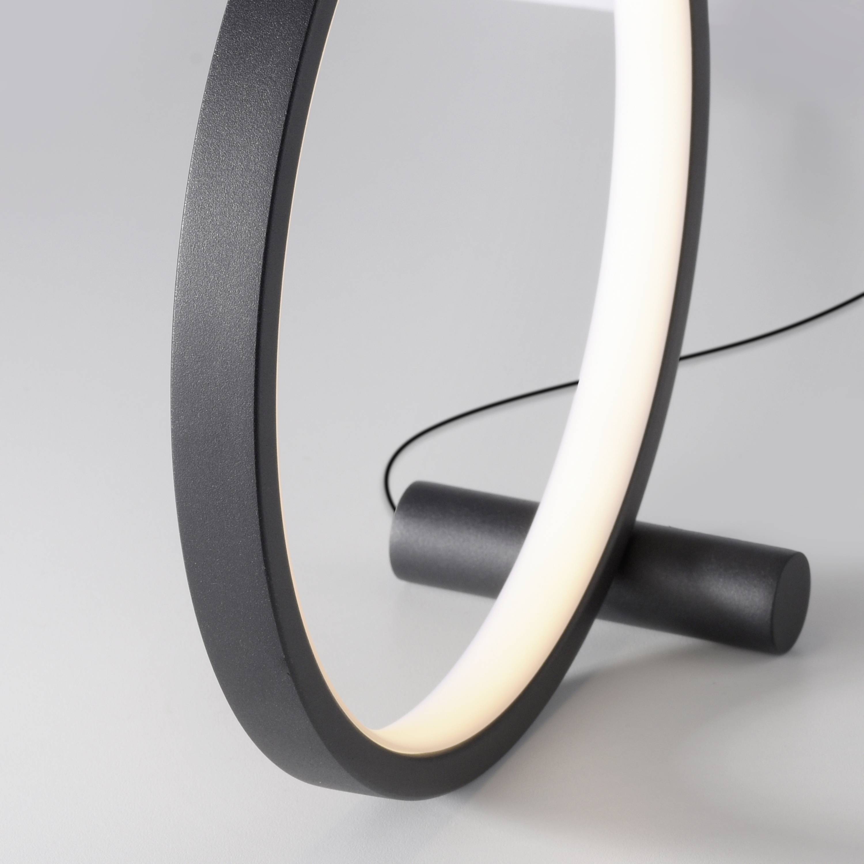 Eine moderne, ringförmige Tischlampe mit schlankem, schwarzem Rahmen und leuchtendem Innenlicht; minimalistisch und stilvoll.