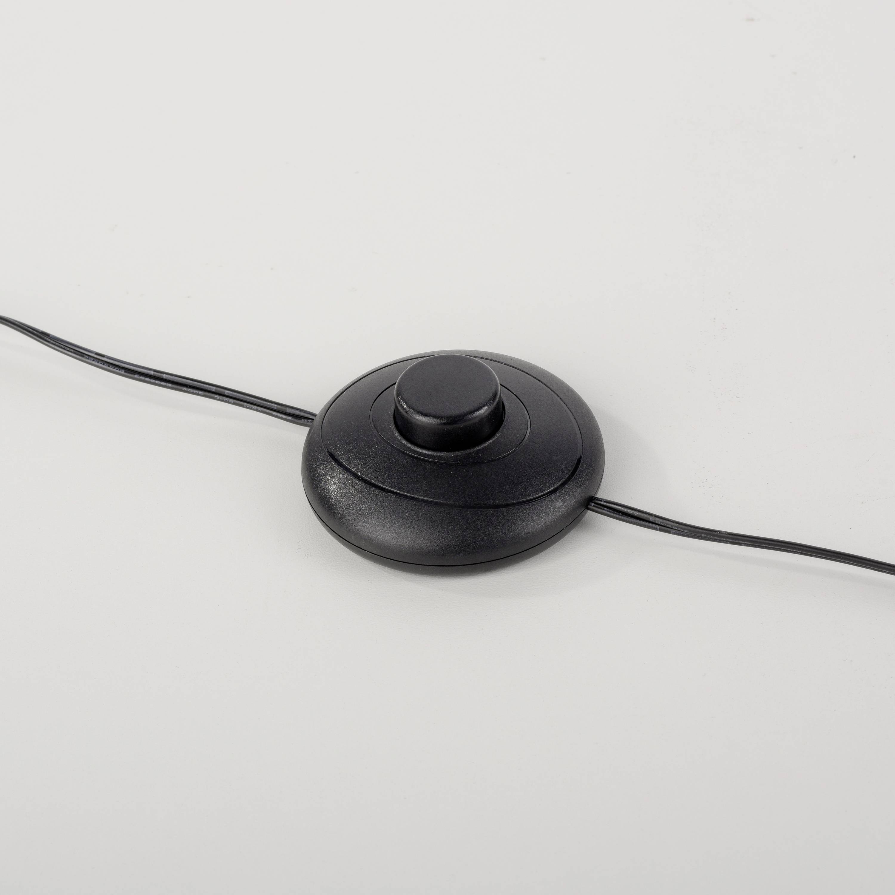 Ein schwarzer Fußschalter mit einem runden Knopf in der Mitte, verbunden mit einem langen Kabel.