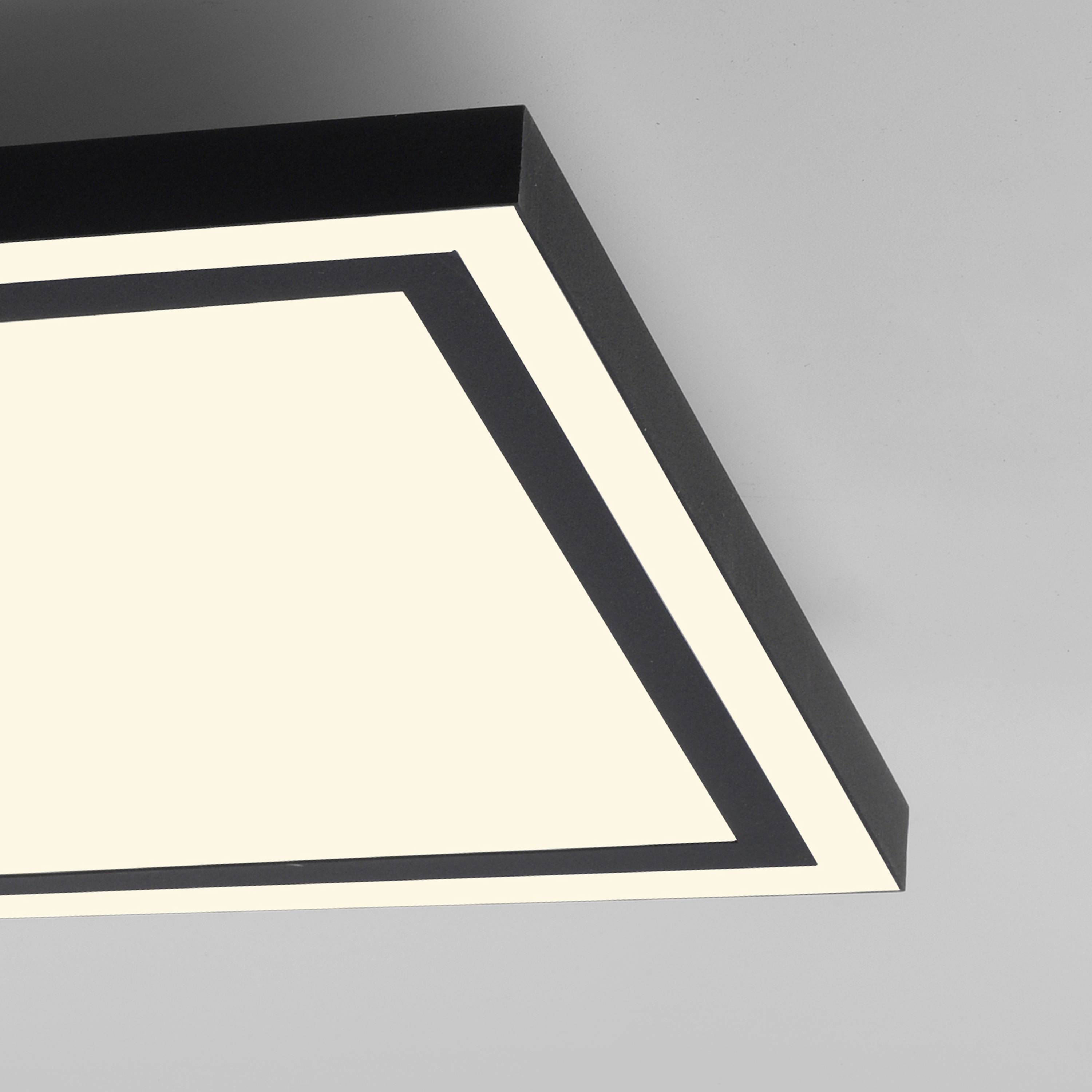 Ein rechteckiges Deckenpanel mit einem leuchtenden, weißen Licht und einem schwarzen Rahmen an einer grauen Decke.