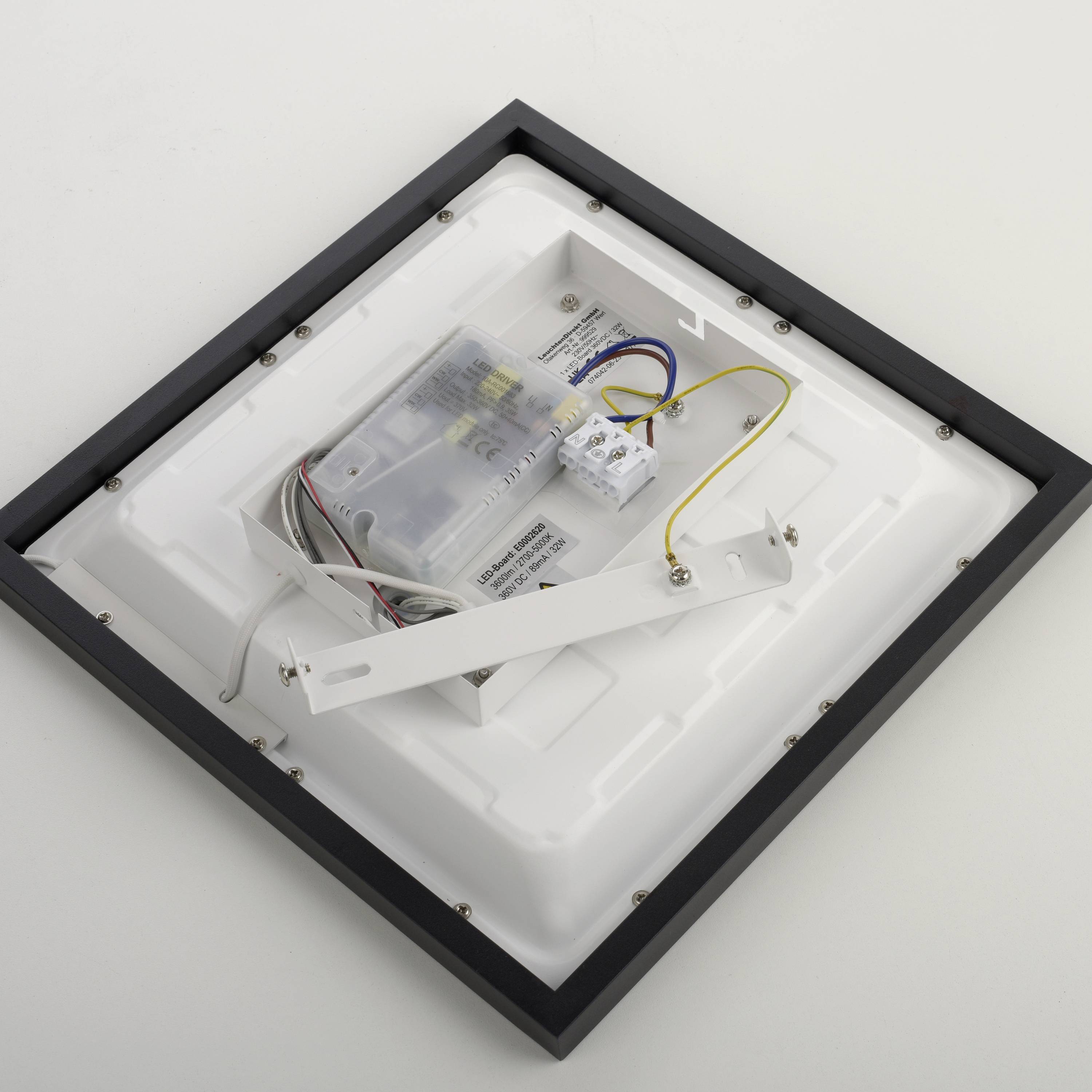 Weiße quadratische LED-Deckenleuchte mit angeschlossenem Kabel und Metallrahmen, auf eine ebenmäßige Oberfläche gelegt.