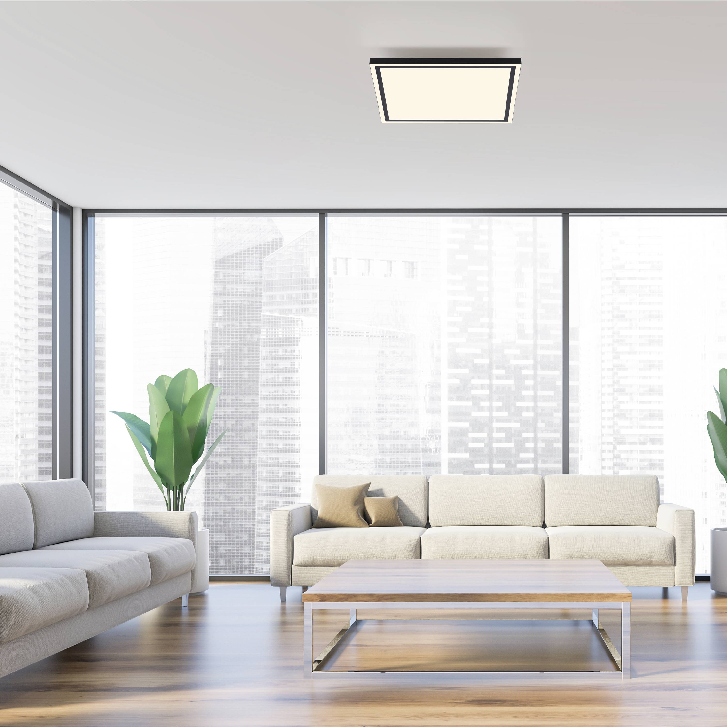 Helles Wohnzimmer mit modernen Sofas, großem Tisch und Panoramafenstern mit Blick auf eine städtische Skyline.