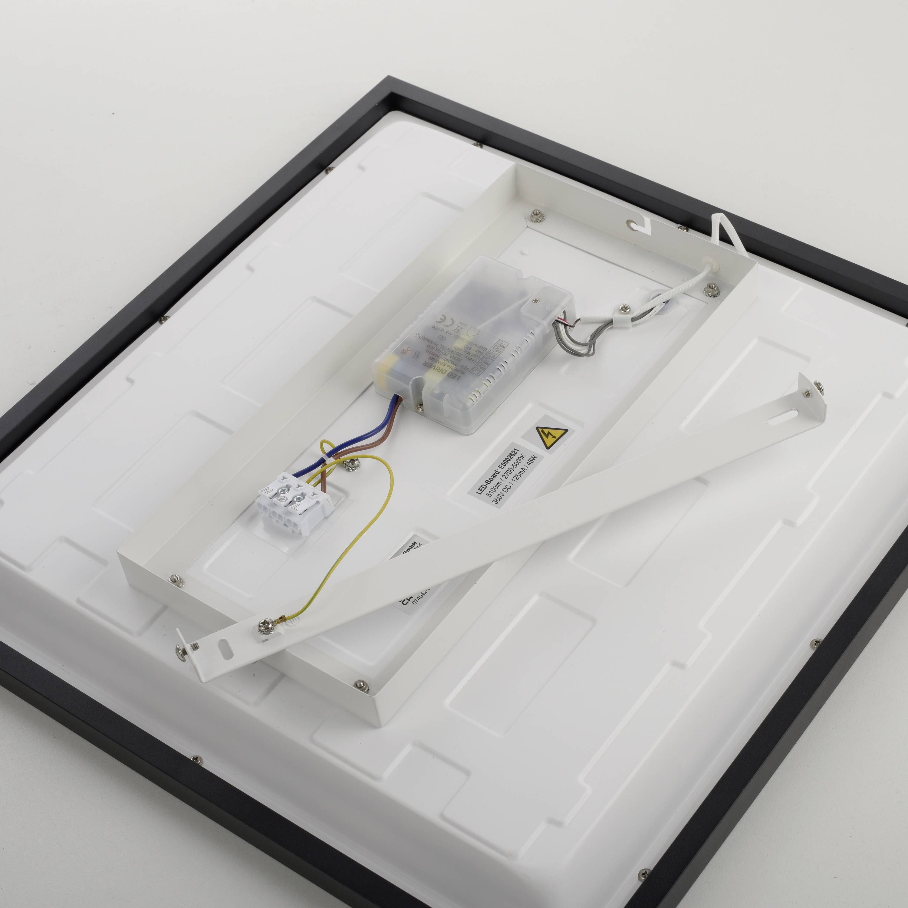 Rückseite eines LED-Panels mit sichtbarer Elektronik und Kabeln, auf einer weißen Fläche liegend. Montagerahmen aus Metall daneben.