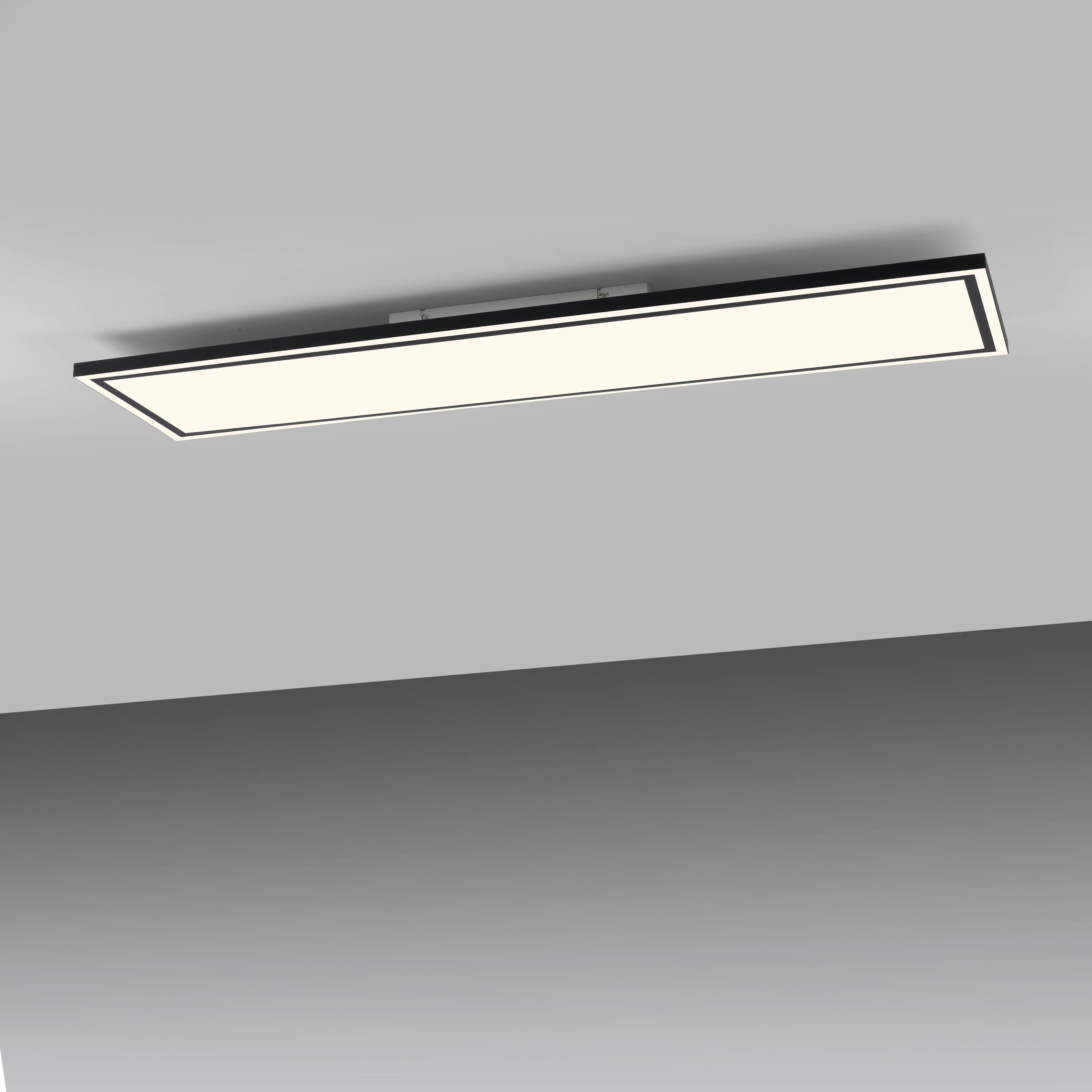 Ein rechteckiges LED-Panel ist in eine graue Decke eingebettet und beleuchtet den Raum.