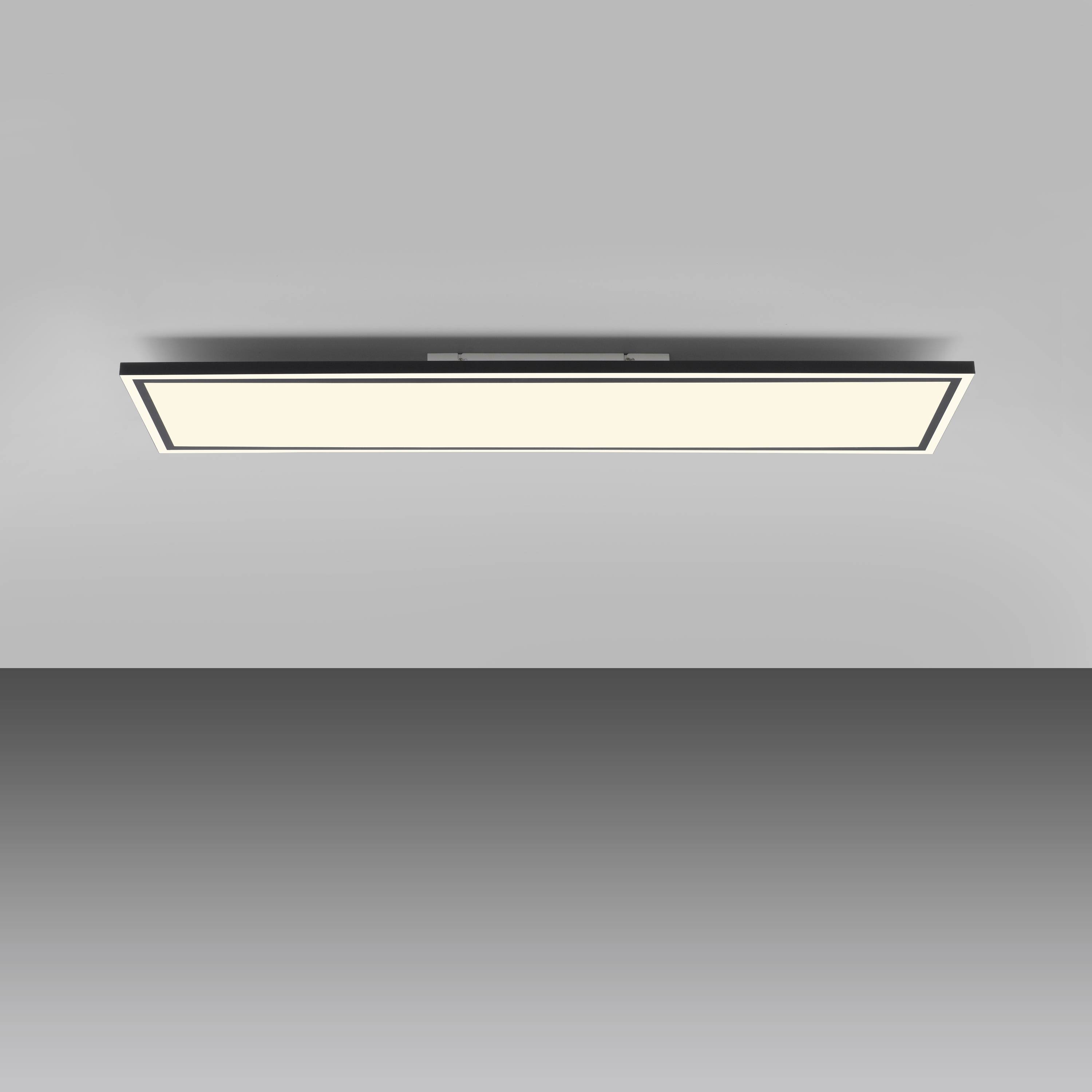 Ein rechteckiges, modernes LED-Deckenlicht vor grauem Hintergrund, eingeschaltet und gleichmäßig hell leuchtend.