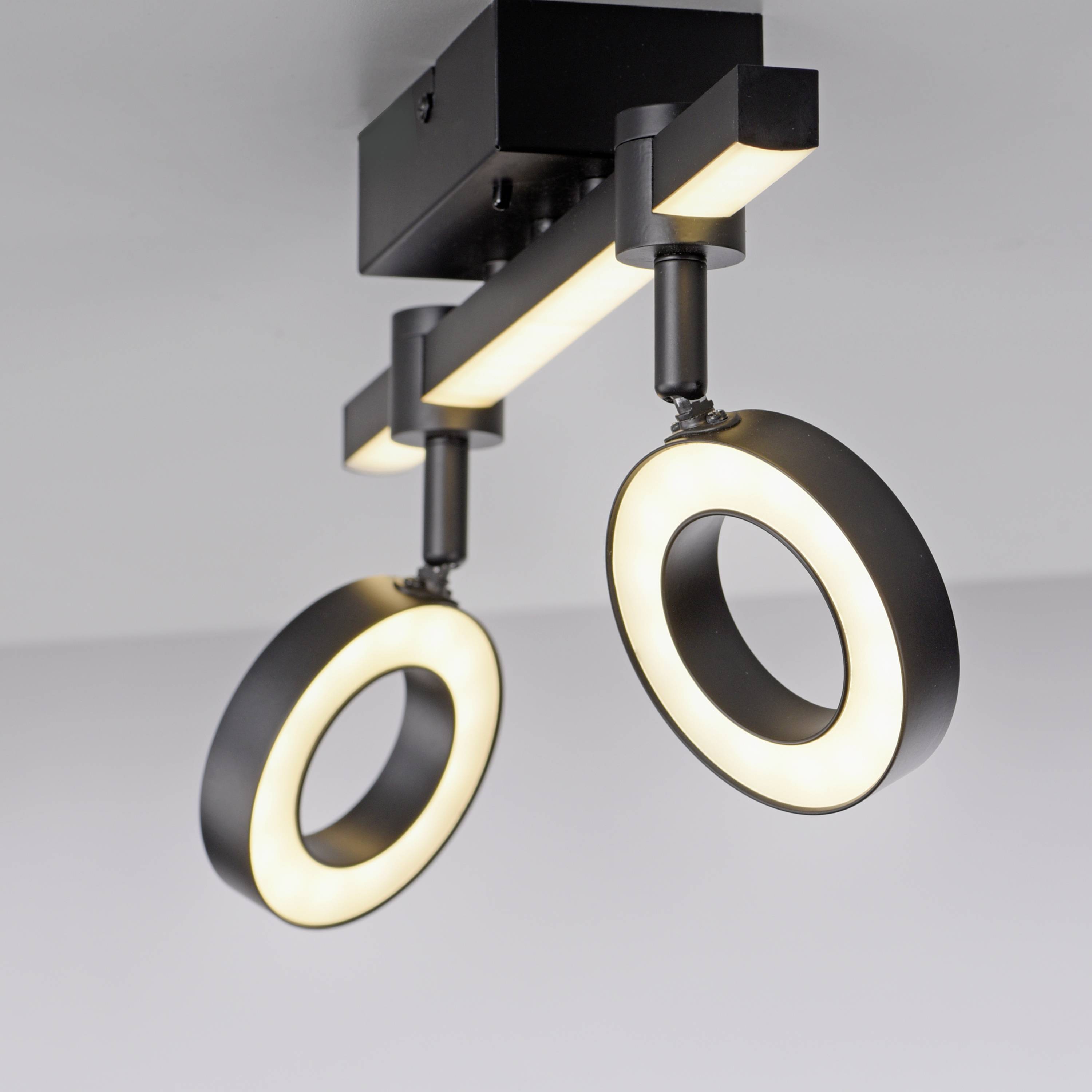 Deckenleuchte mit zwei kreisförmigen, leuchtenden Ringen, modern und schwarz gestaltet, an einer Halterung montiert.