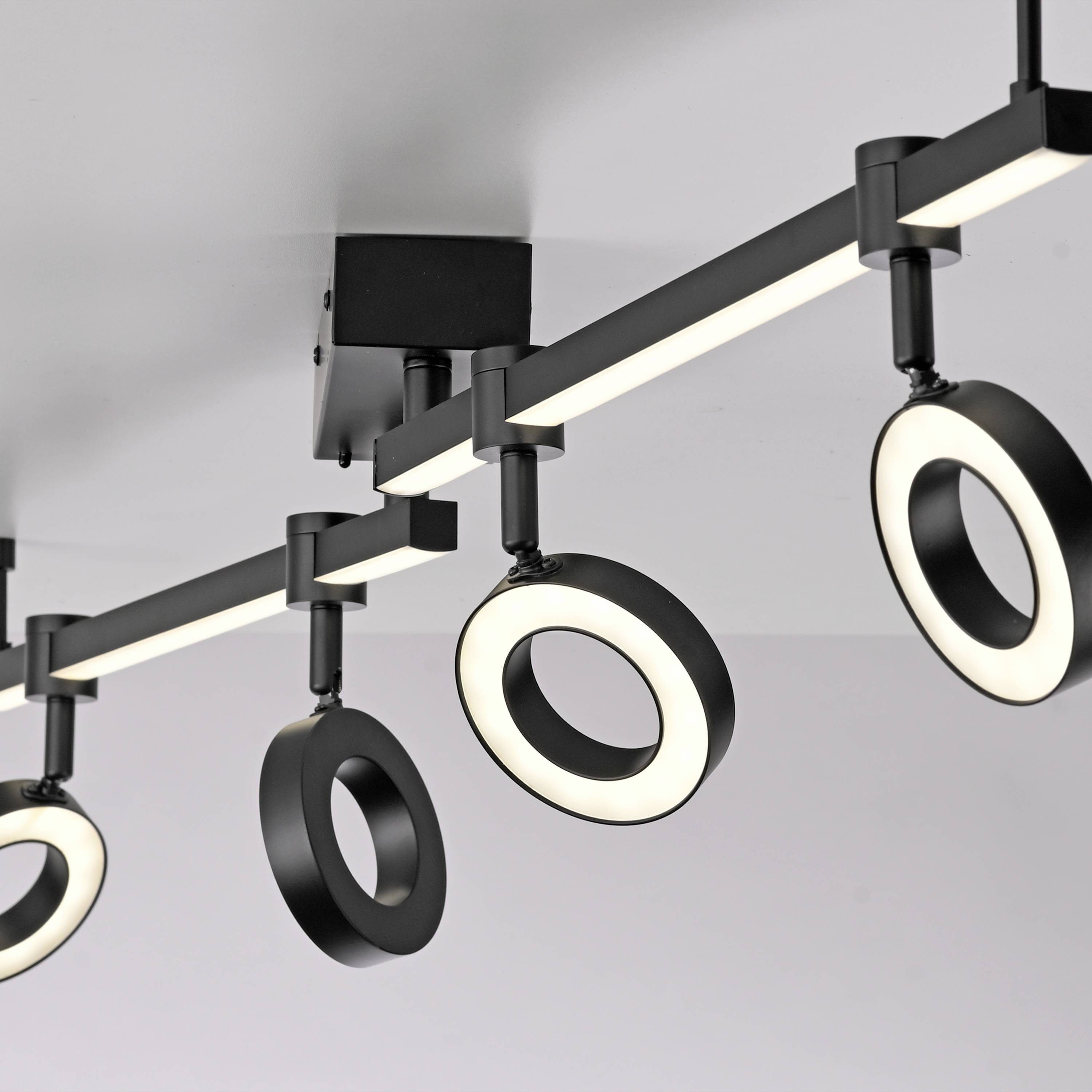 Eine moderne, schwarze Deckenleuchte mit drei runden LED-Leuchten, die an einem geraden Balken hängen, montiert an einer weißen Decke.