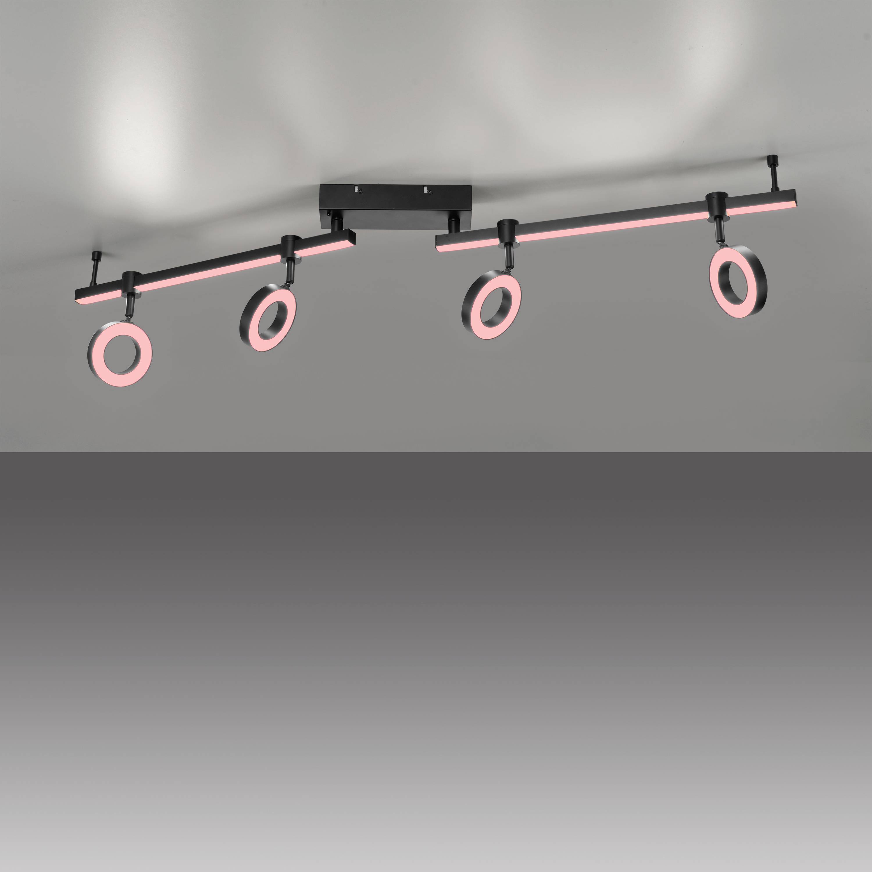 Eine moderne Deckenleuchte mit drei ringförmigen rosa leuchtenden Lampen an schwarzen Stangen, die an einer rechteckigen Basis befestigt sind.