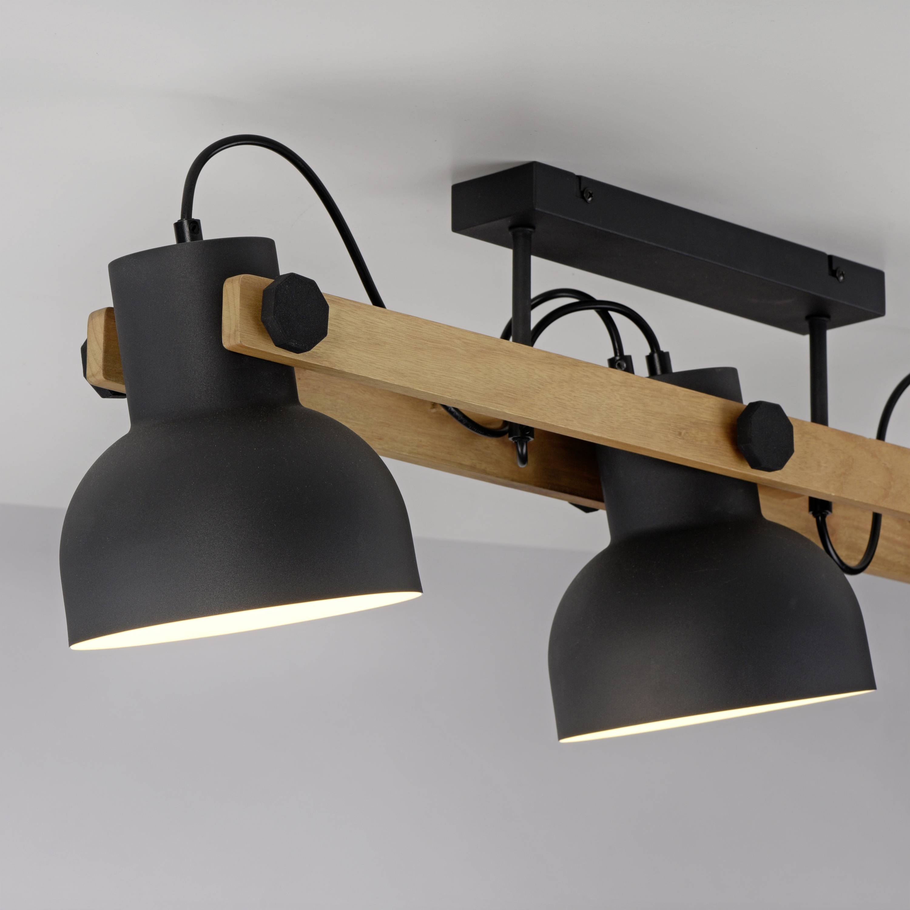 Zwei schwarze Deckenleuchten mit Holzhalterung sind an der Decke montiert und beleuchten den Raum gleichmäßig.