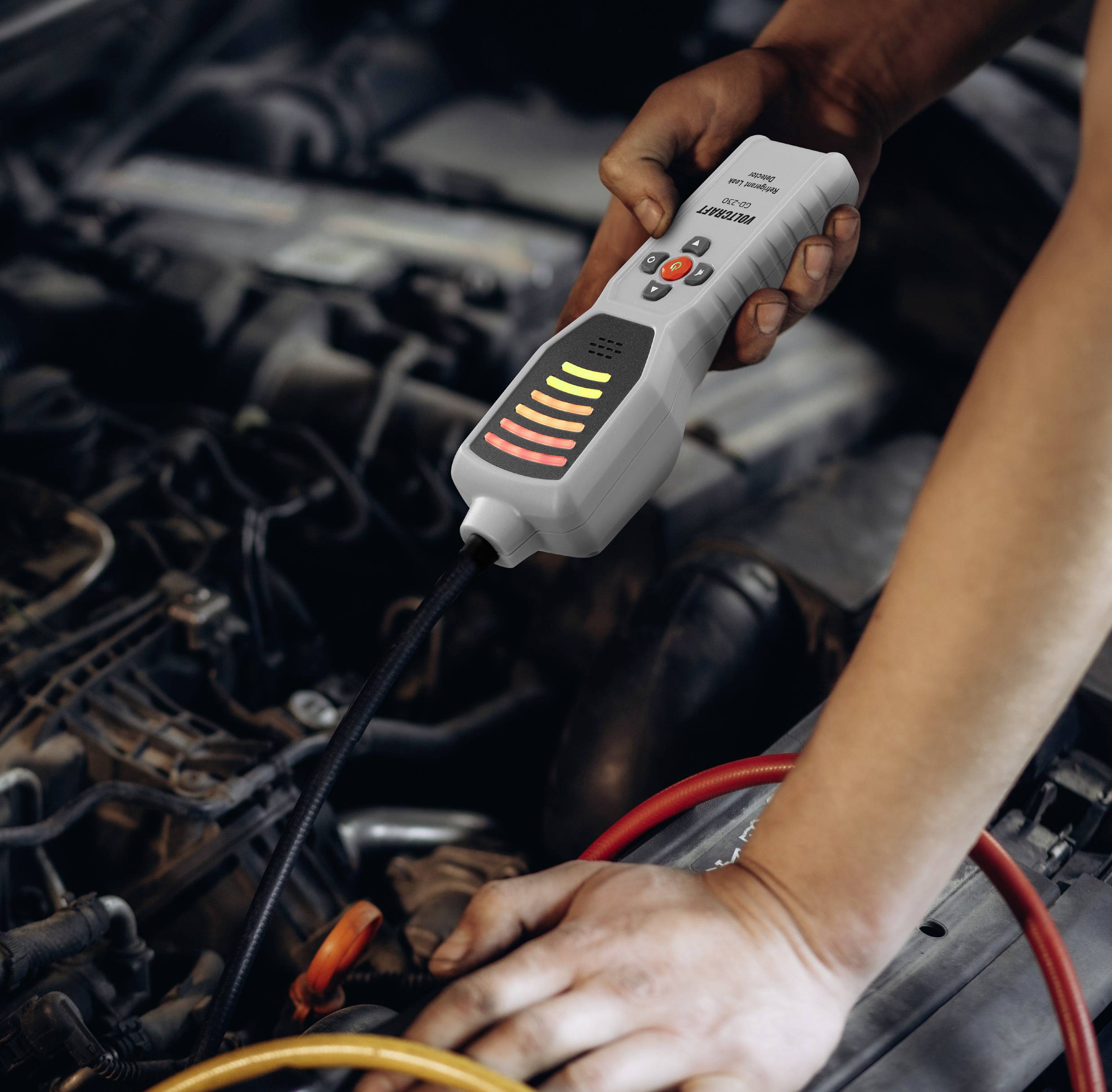 Eine Person, die ein tragbares Diagnosegerät an einem Automotor verwendet und nach Problemen sucht. Das Gerät zeigt Ergebnisse mit leuchtenden Indikatoren an.