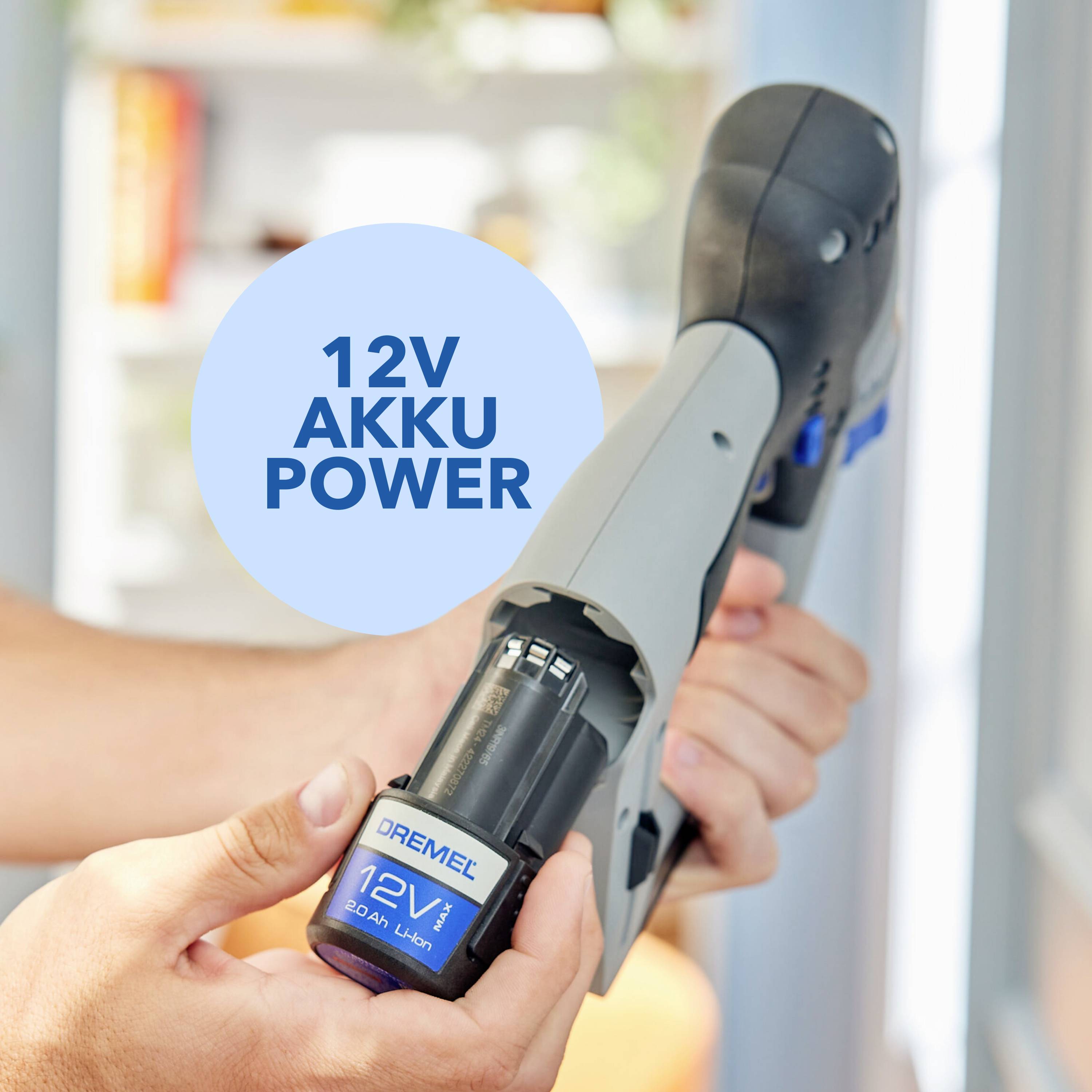 Eine Hand hält ein 12V Dremel-Werkzeug mit eingelegtem Akku; ein blauer Kreis auf der Oberseite enthält den Text '12V Akku Power'.