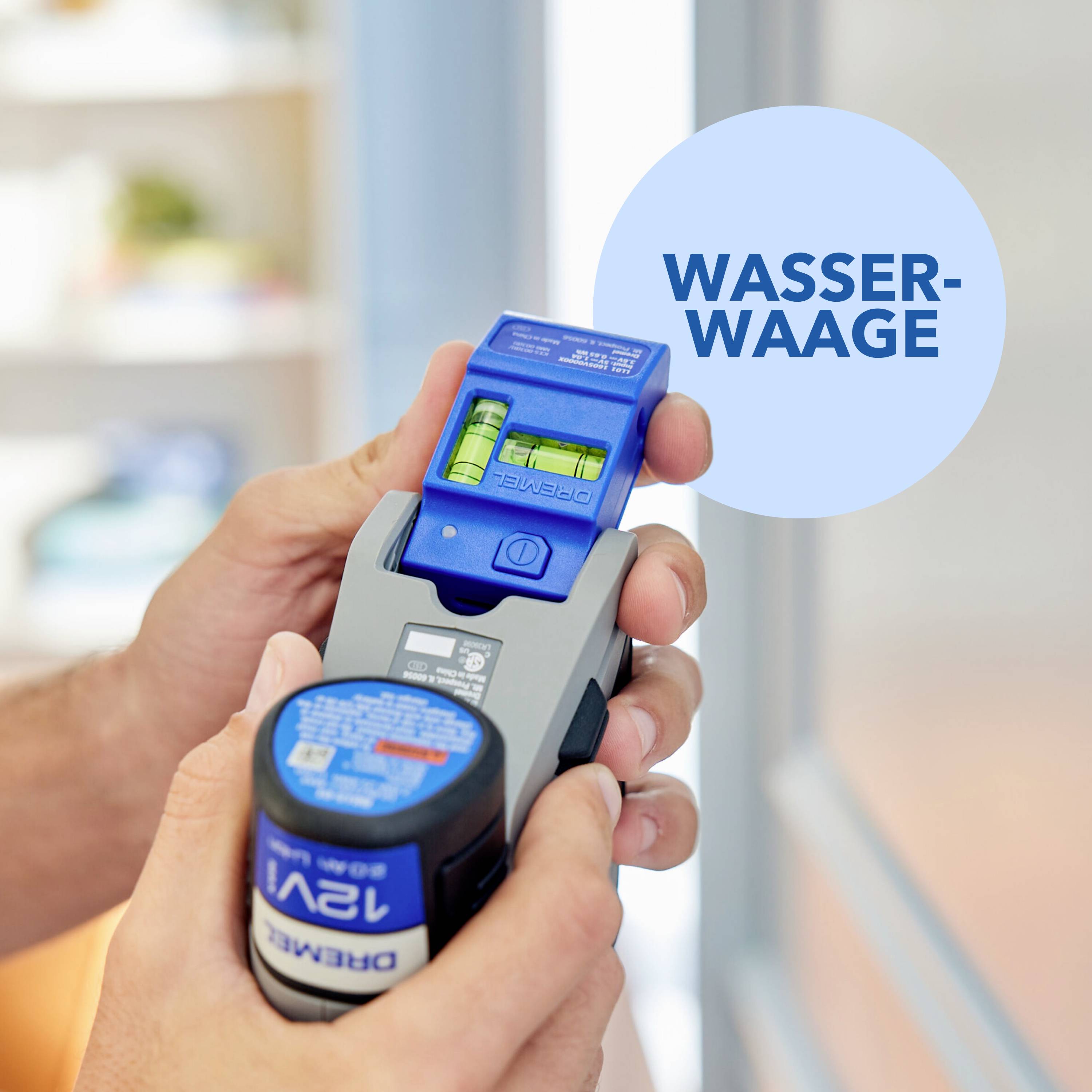 Eine Person hält ein blau-graues Messgerät mit einer Wasserwaage. Im Hintergrund ist ein verschwommenes Fenster zu sehen.