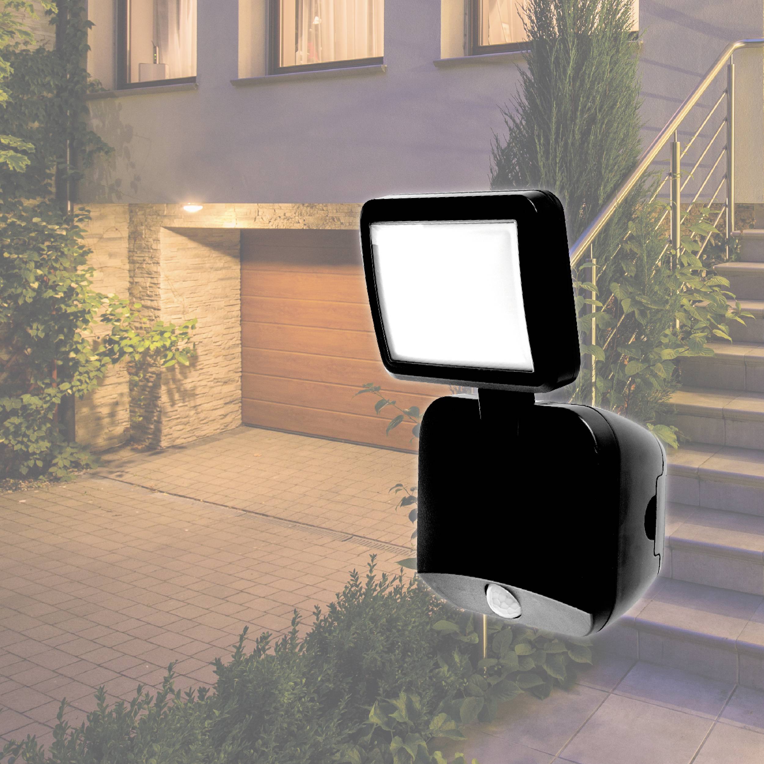 Außenleuchte mit Bewegungsmelder erhellt nachts eine Hausfassade. Die Beleuchtung erhellt den Eingangsbereich und eine Treppe.