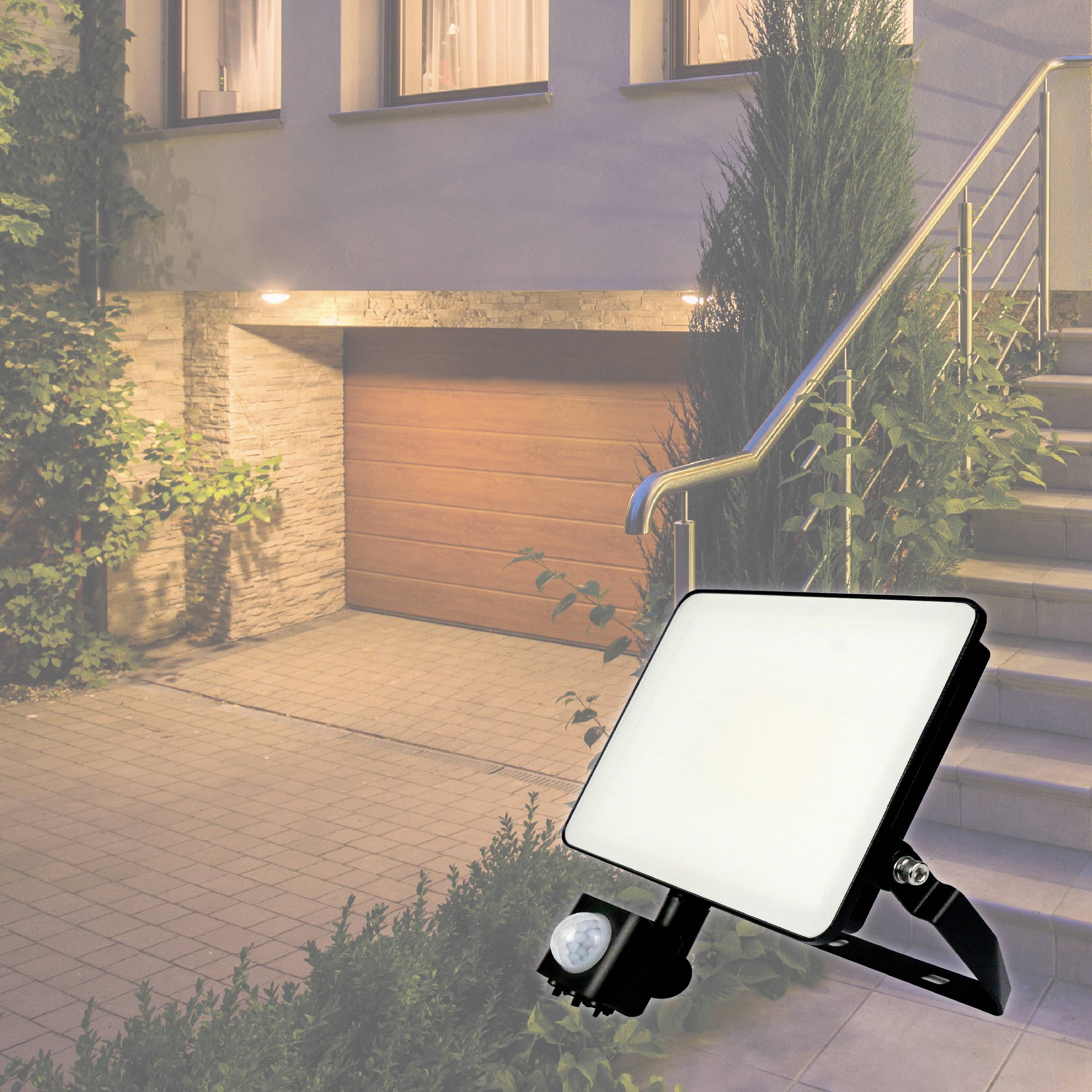 Ein heller LED-Strahler beleuchtet eine Garagenauffahrt neben einem Treppenaufgang.