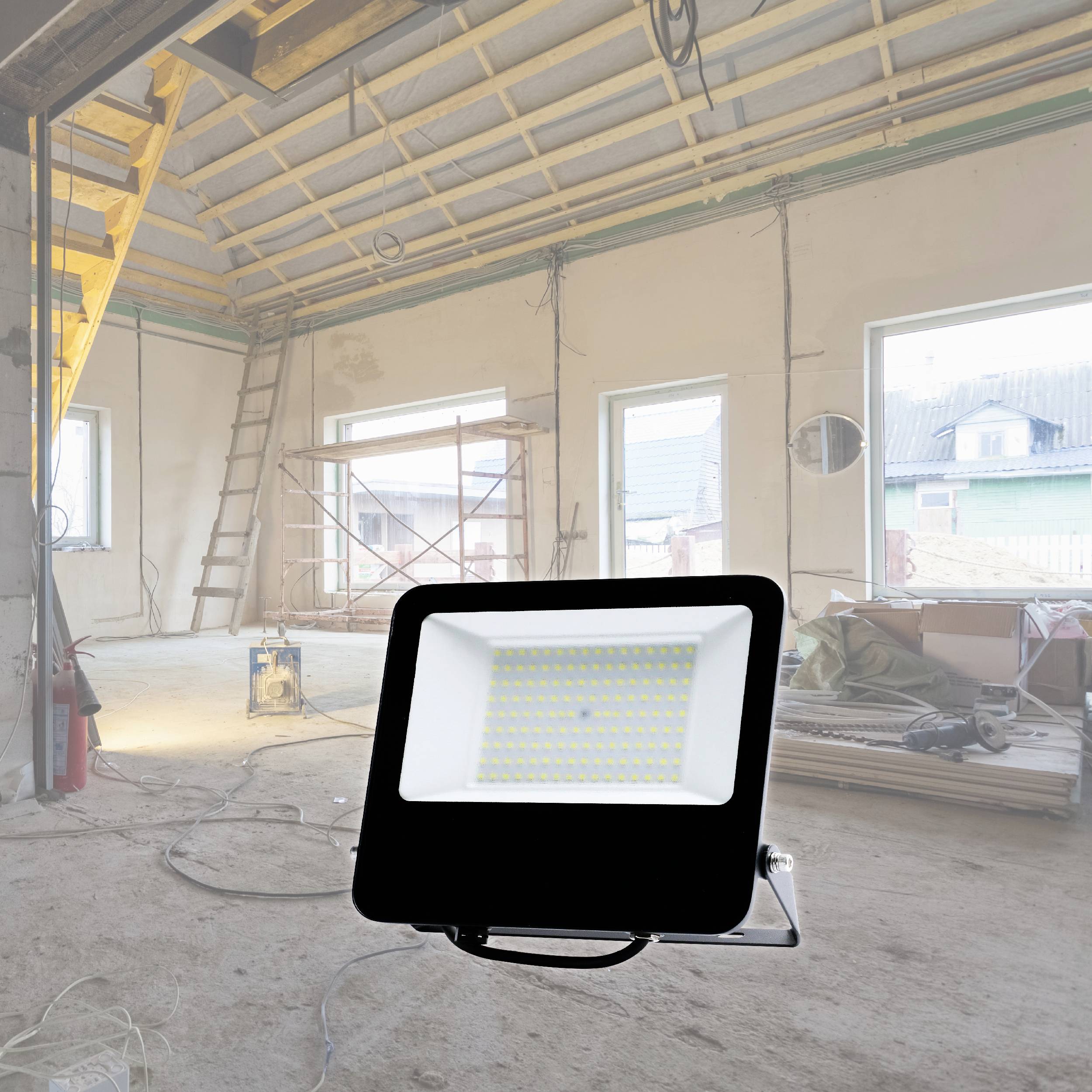 Renovierungsraum mit Baustellenlampe im Vordergrund, Baumaterialien, Leitern und Gerüste im Hintergrund. Arbeiter nicht sichtbar.