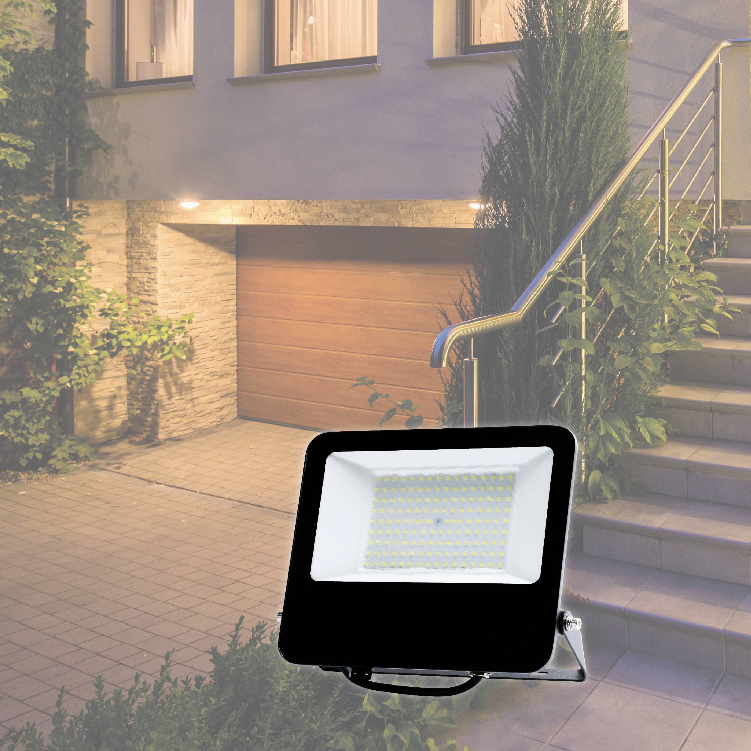 Ein LED-Flutlicht beleuchtet den Eingang eines Hauses mit Garage, Treppe und Pflanzen an der Seite.