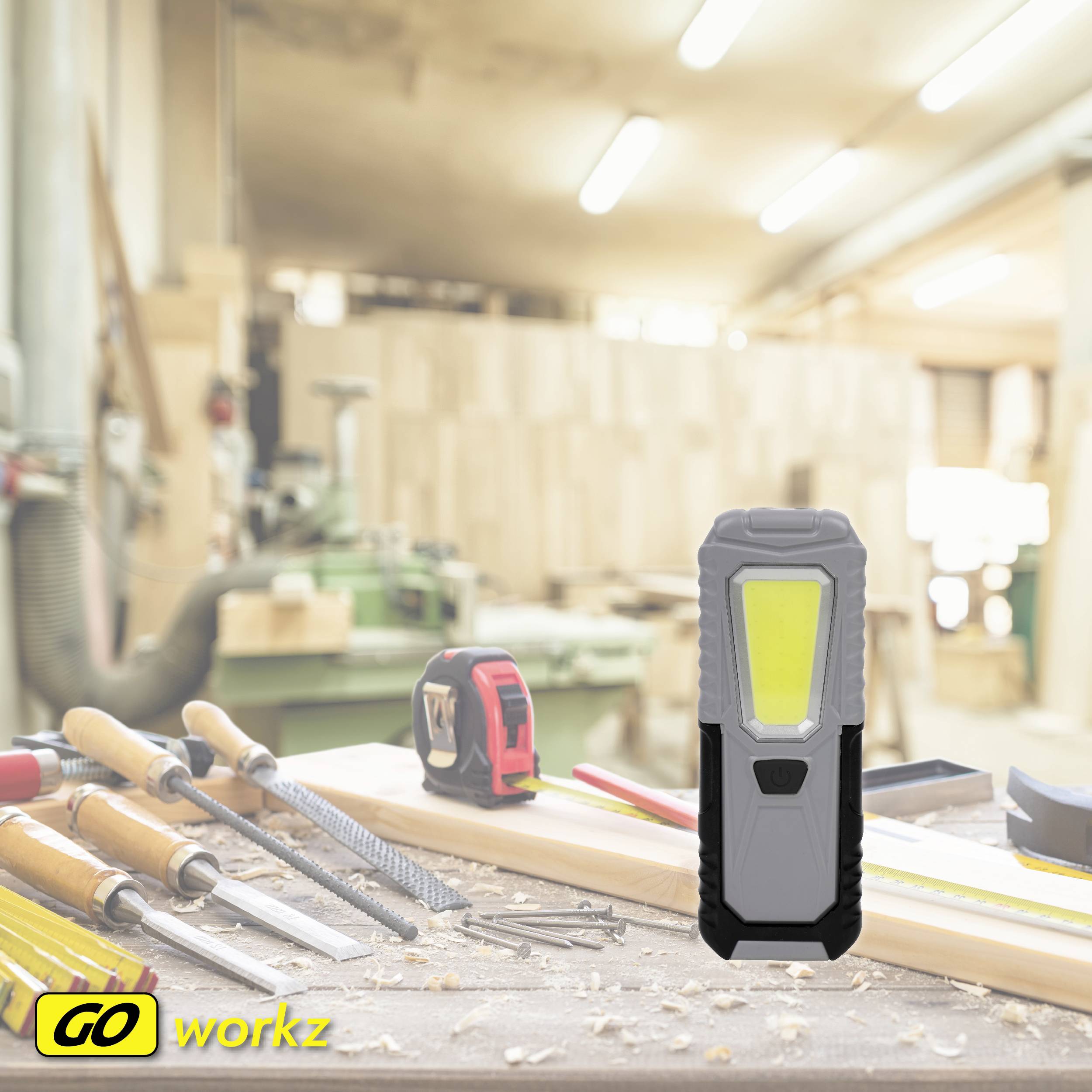 Werkstatt mit Werkzeugen auf einem Tisch; im Vordergrund eine formschöne, ergonomische Lampe; Hintergrund unscharf mit Regalen.