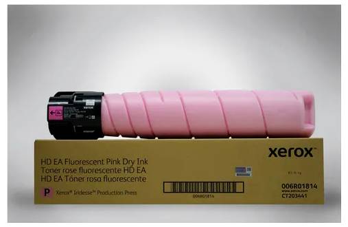 Eine rosa Xerox-Tonerkartusche liegt auf einer Verpackung. Der Karton zeigt Aufdrucke wie 'HD EA Fluorescent Pink Dry Ink'.