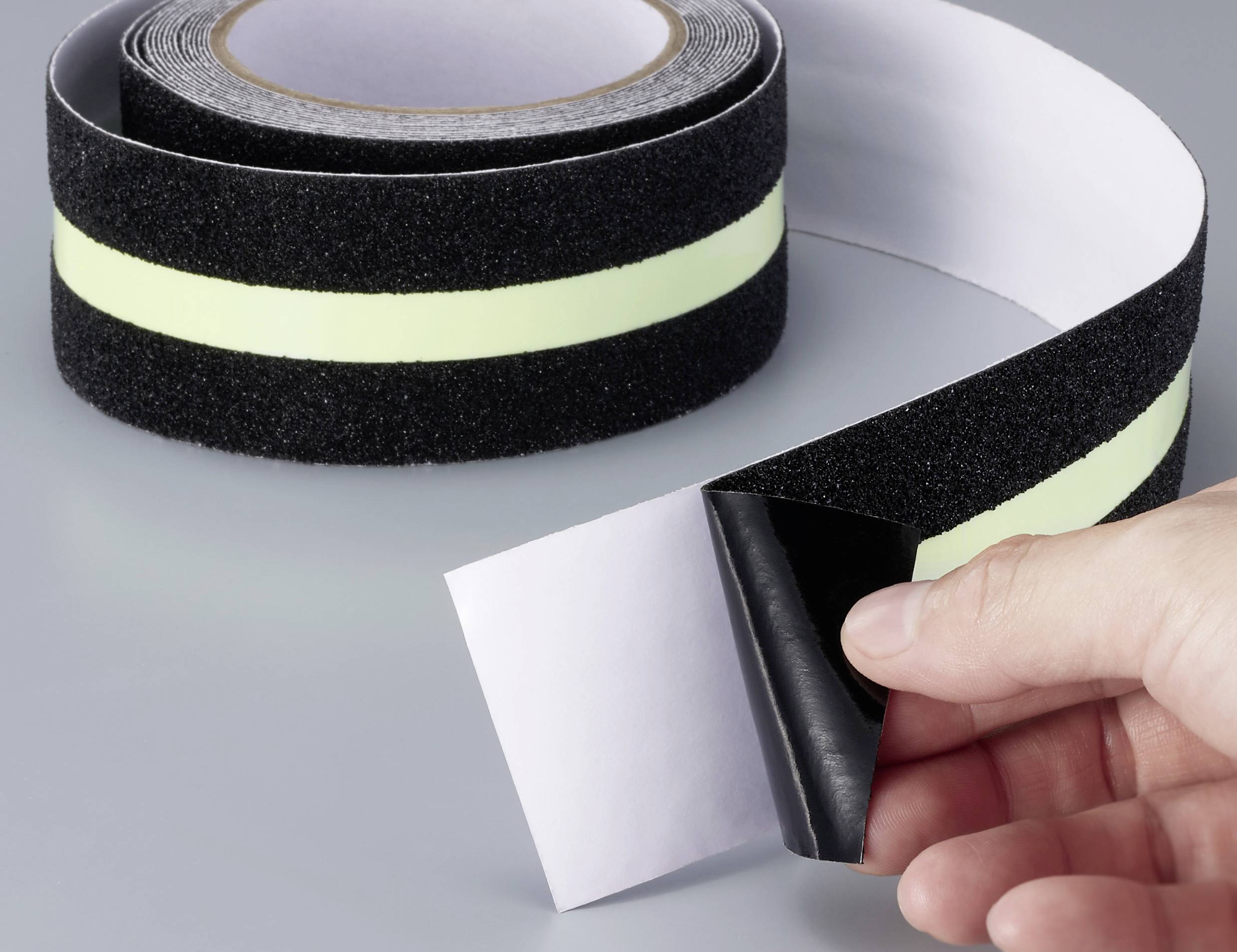 Jemand hält ein breites, schwarzes Klettband mit reflektierendem Streifen.