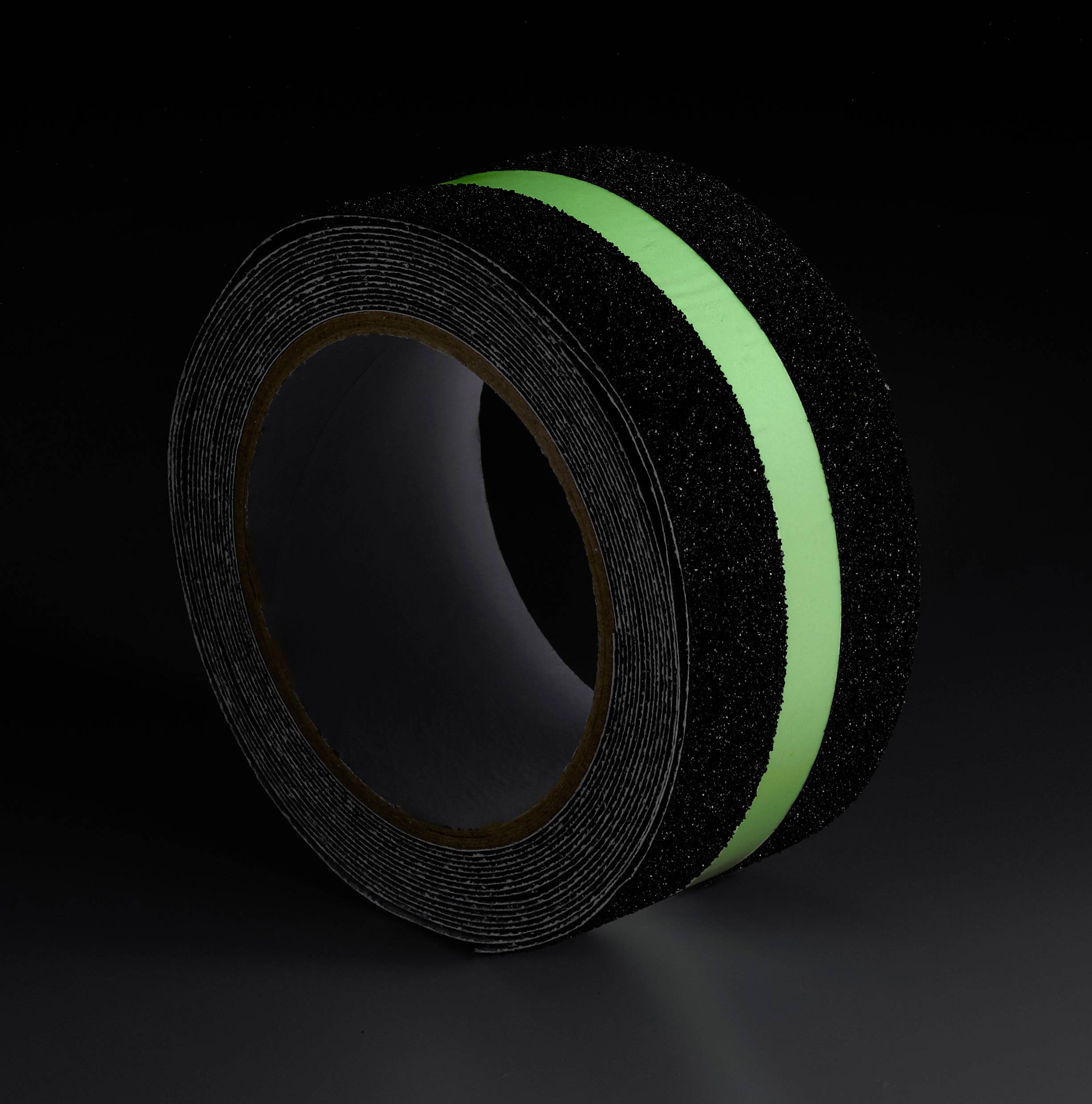 Schwarzes Klebeband mit grünem fluoreszierendem Streifen, aufgerollt auf einem dunklen Hintergrund.