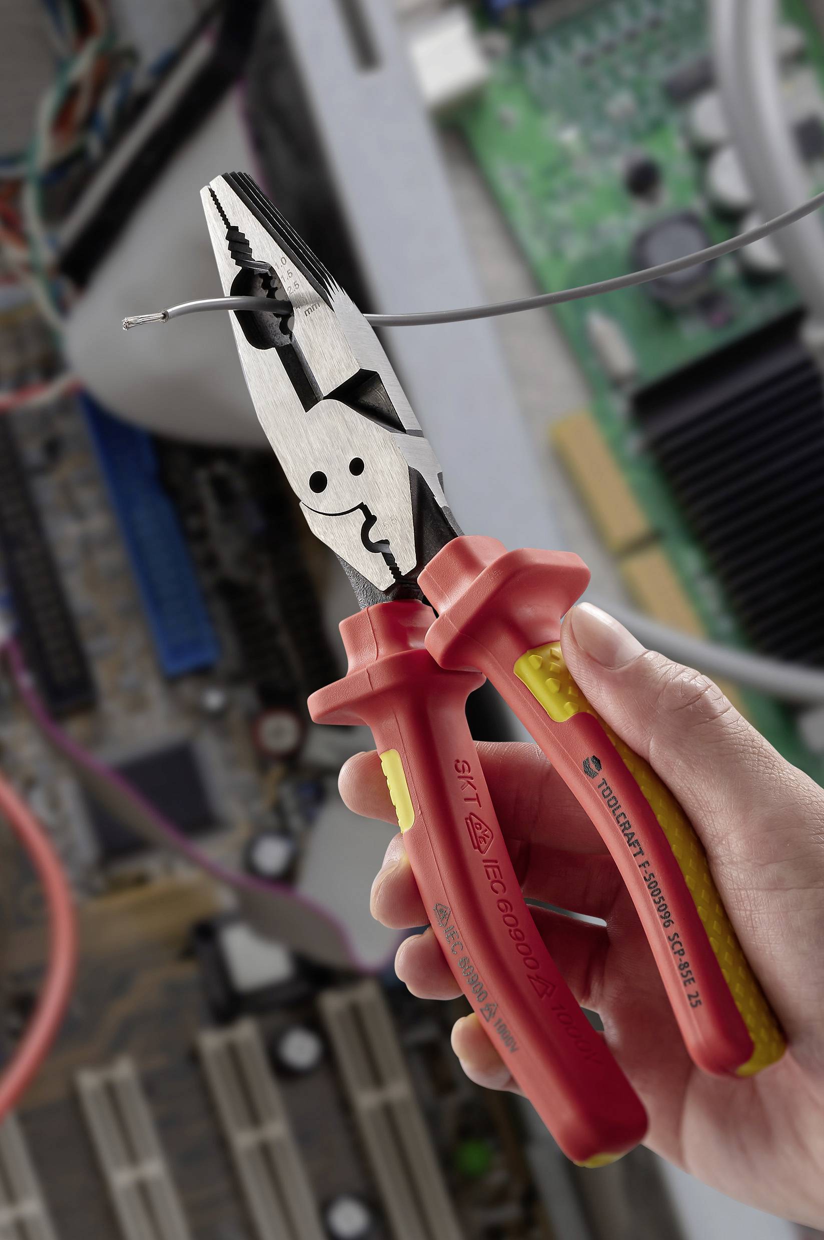 Eine Hand hält Zangen mit roten Griffen und durchtrennt einen Draht in einem geöffneten Computer mit sichtbaren Leiterplatten und Komponenten.