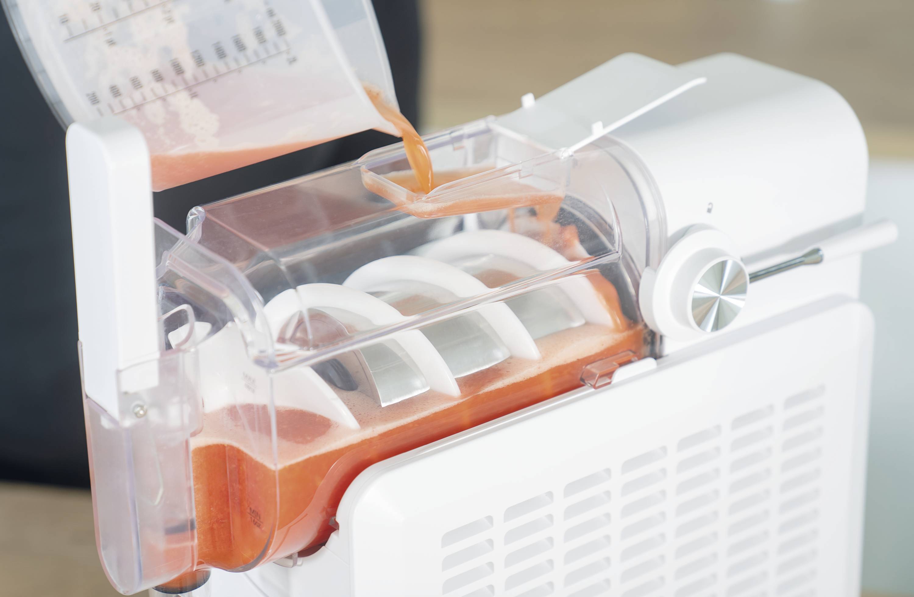 Eine Maschine produziert frische Pasta; der Teig wird in eine Form gegossen. Die Umgebung ist sauber und modern.