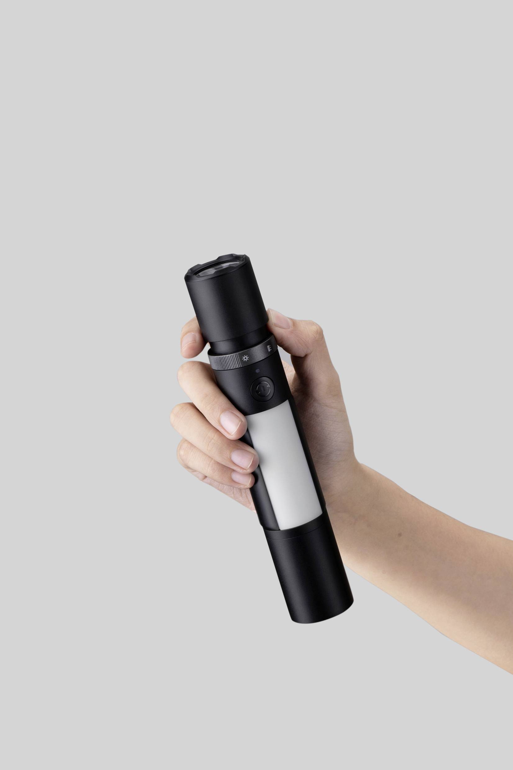 Eine Hand hält eine stilvolle schwarze und weiße Taschenlampe vor grauem Hintergrund.