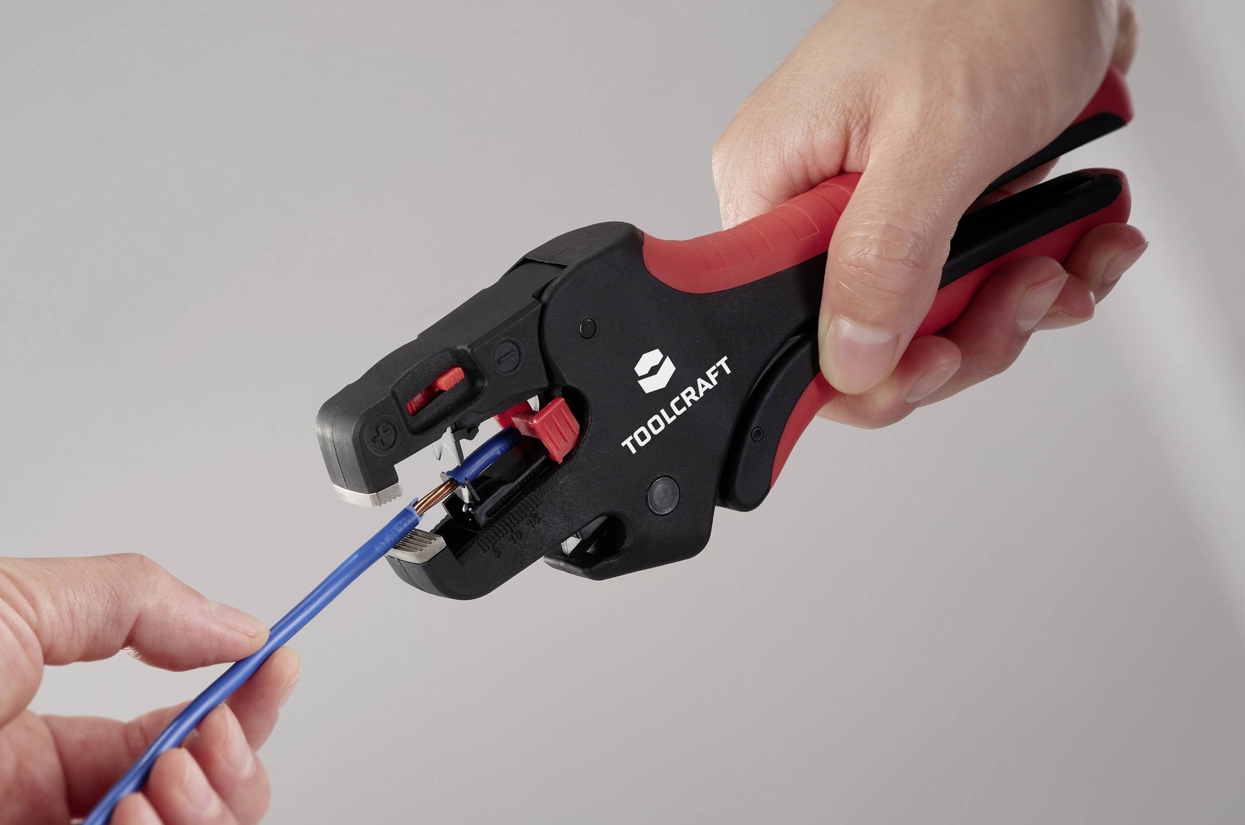 Eine Person verwendet ein rot-schwarzes Werkzeug mit der Aufschrift 