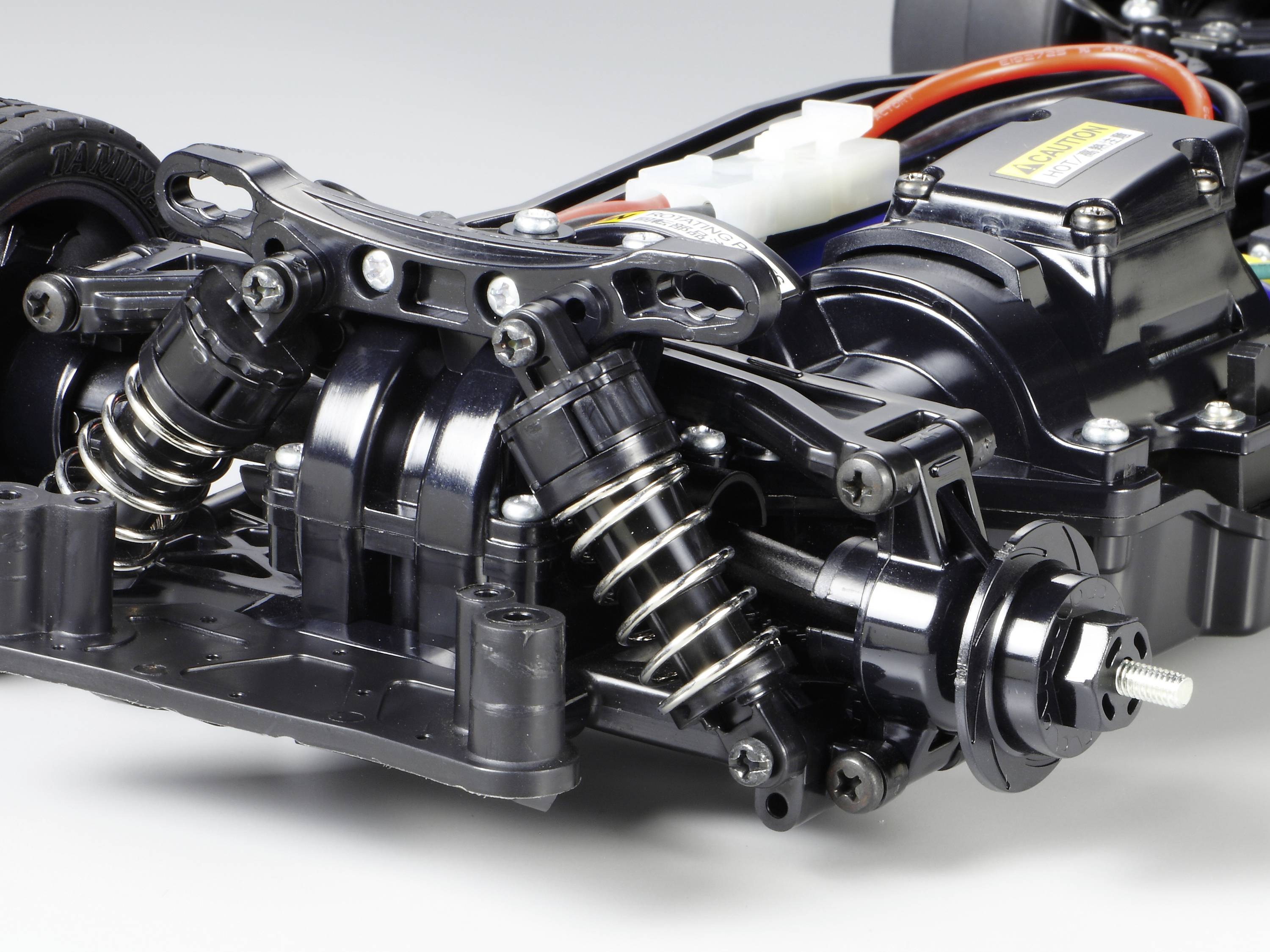 Nahaufnahme eines ferngesteuerten Auto-Chassis mit sichtbaren Stoßdämpfern und Motor. Fokus liegt auf Federungskomponenten.