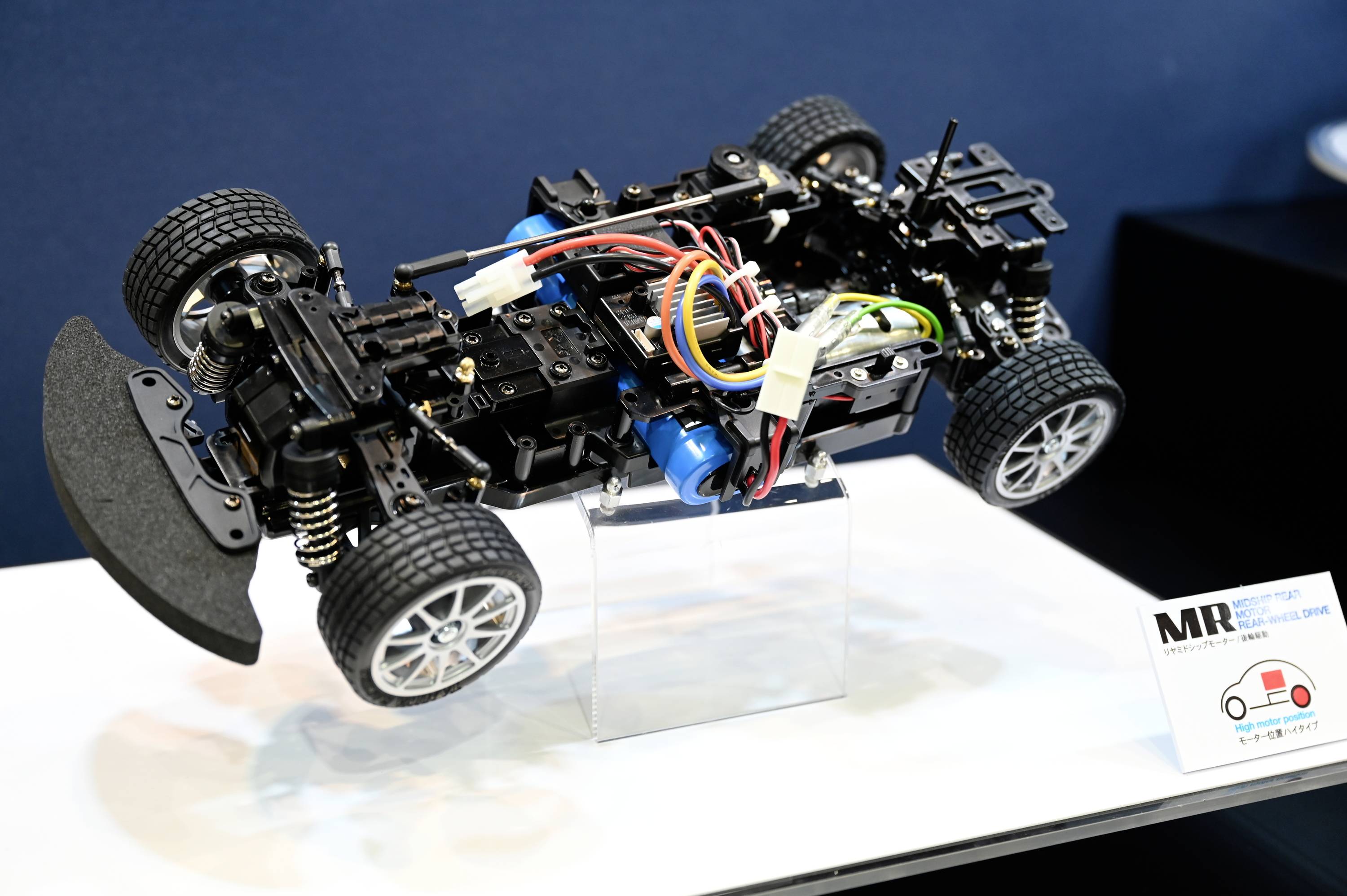 RC-Auto-Chassis im Detail: Aufhängung, Elektronik und Verkabelung gut sichtbar. Präsentationsrahmen mit kleinem Diagramm auf der Seite.