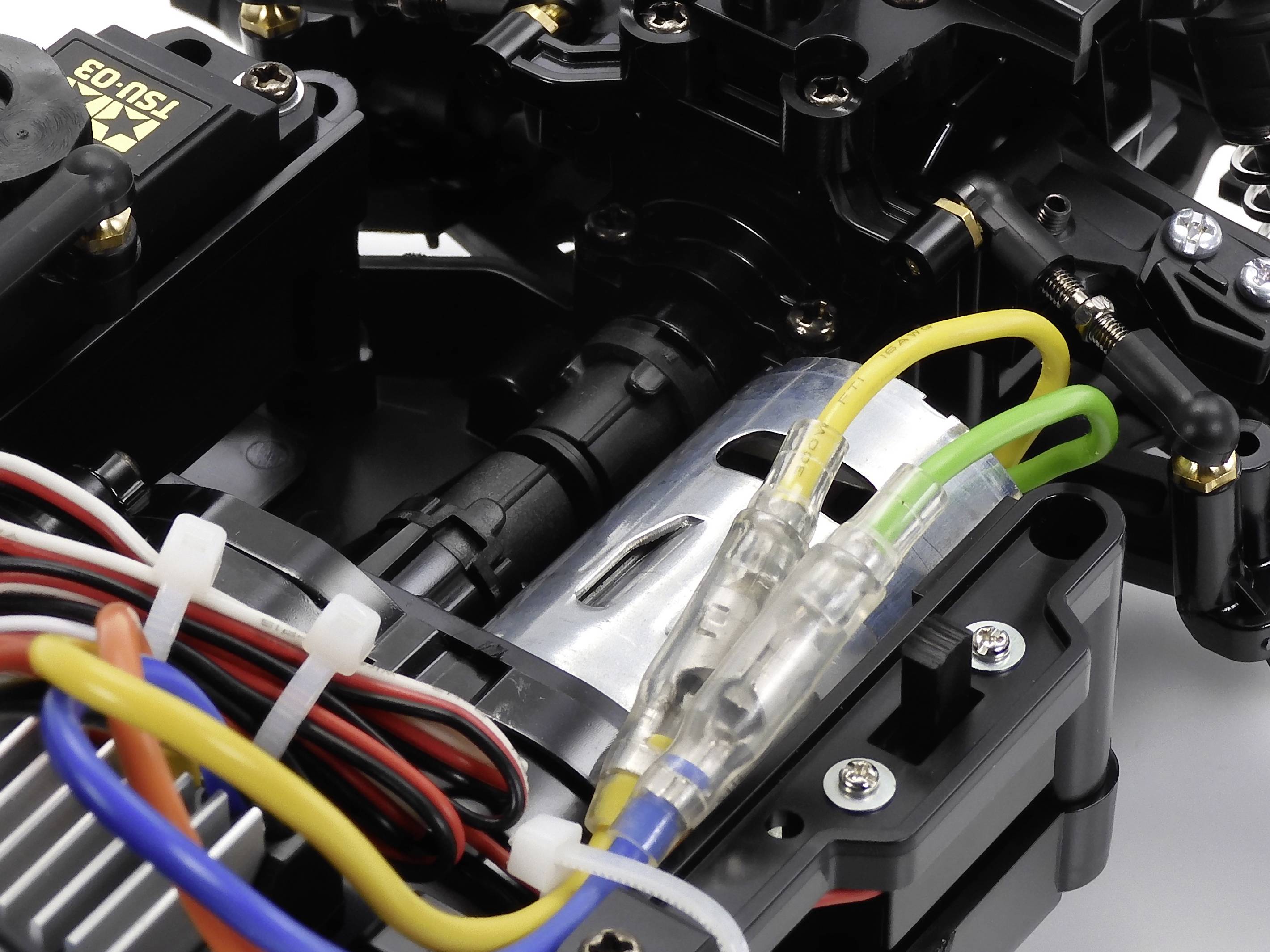 Nahaufnahme eines ferngesteuerten Auto-Chassis mit sichtbaren bunten Drähten und mechanischen Komponenten.