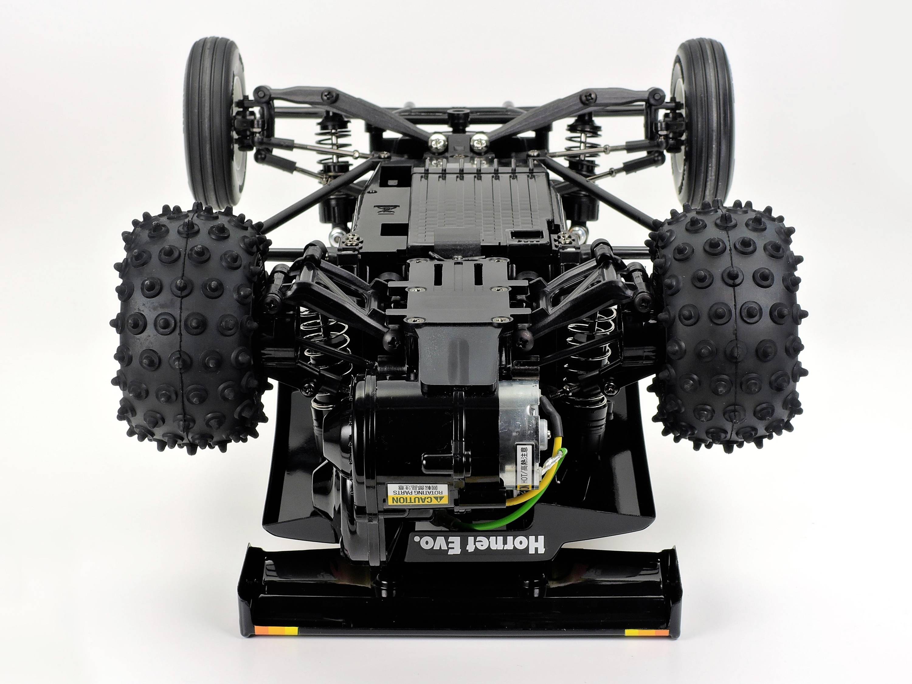 Ein ferngesteuertes Auto, das auf dem Kopf steht und die detaillierte Mechanik und Radaufhängung zeigt.