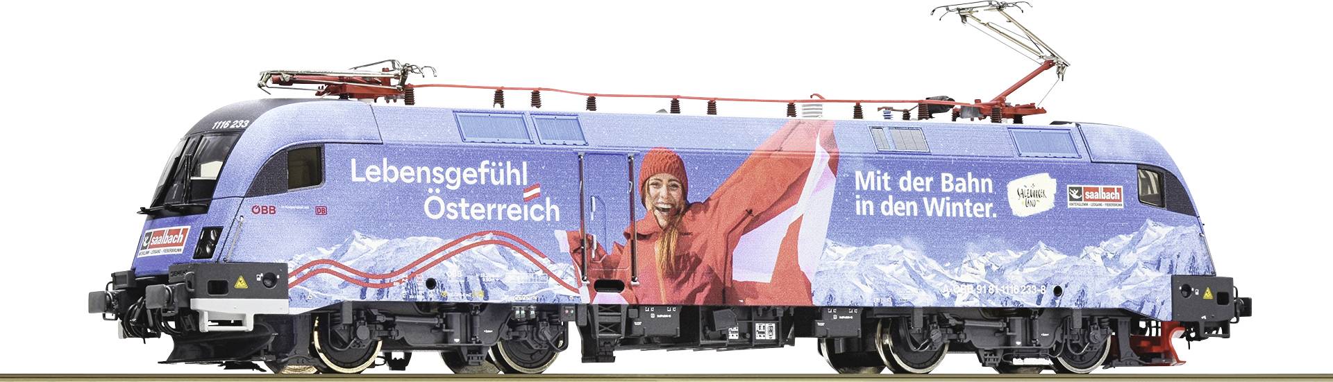 Blaue Lokomotive mit Werbung für den Wintertourismus in Österreich, zeigt eine lächelnde Person in roter Winterkleidung vor Bergen.
