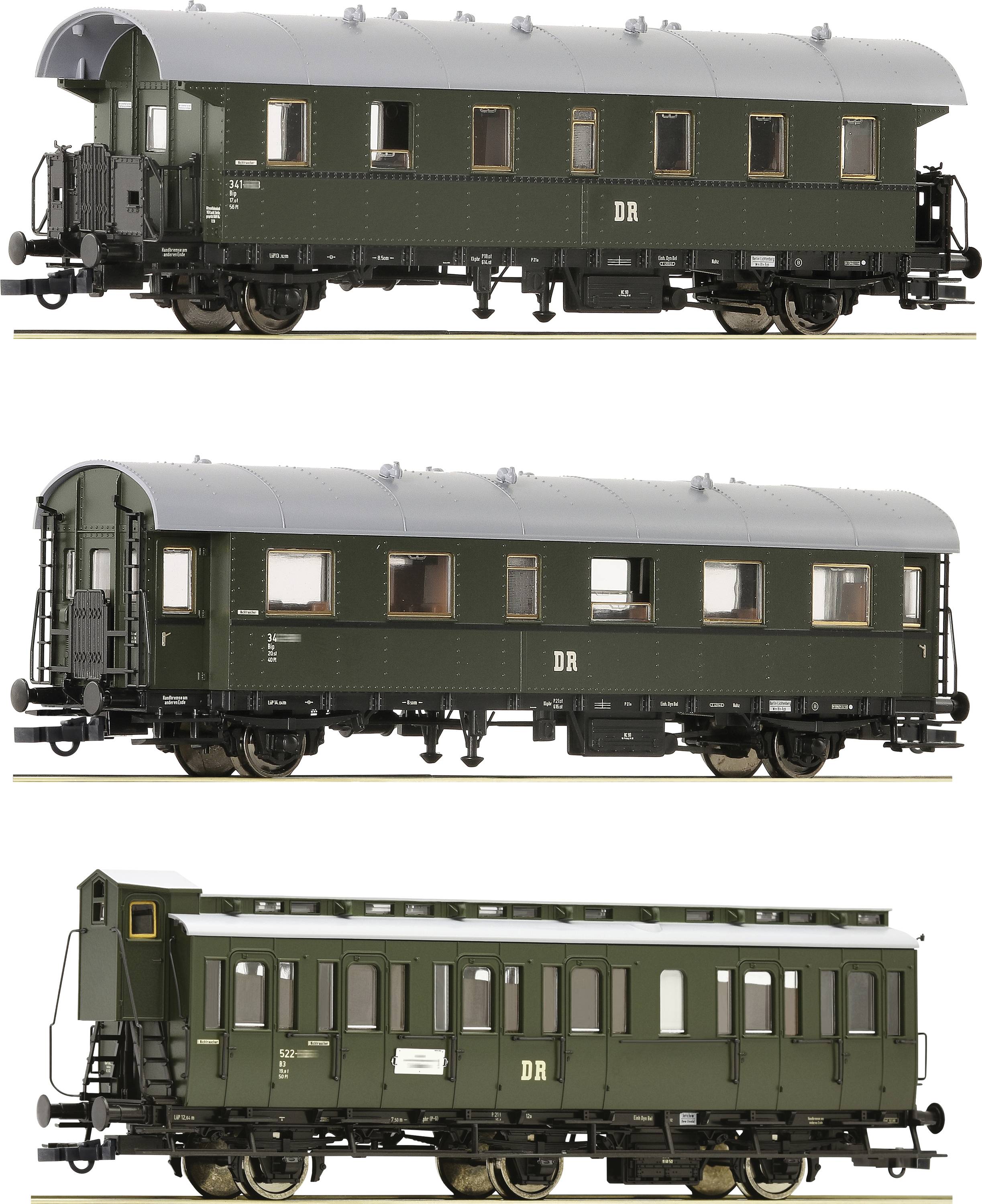 Drei historische grüne Eisenbahnwaggons der Deutschen Reichsbahn, in unterschiedlichen Bauarten, stehend nebeneinander.