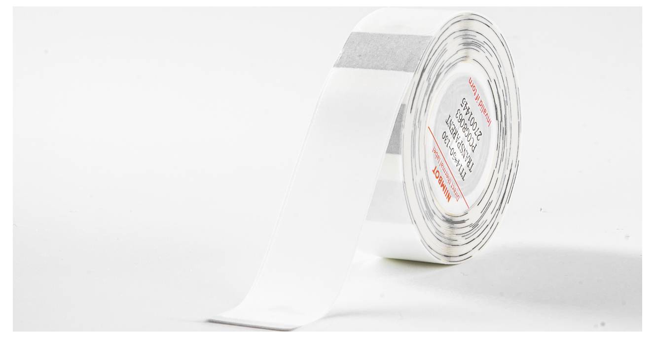 Eine Rolle weißen Klebebands, teilweise abgerollt, liegt auf einer weißen Oberfläche.