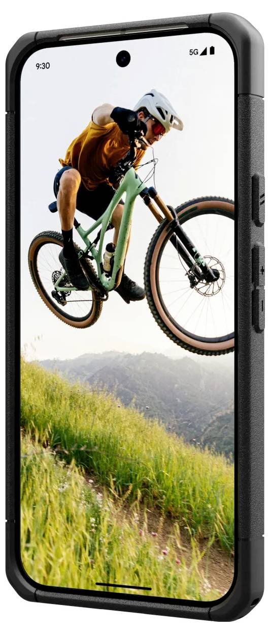 Ein Mountainbiker springt in der Luft vor einer Berglandschaft. Im Vordergrund ist das Foto auf einem Smartphone-Display zu sehen.
