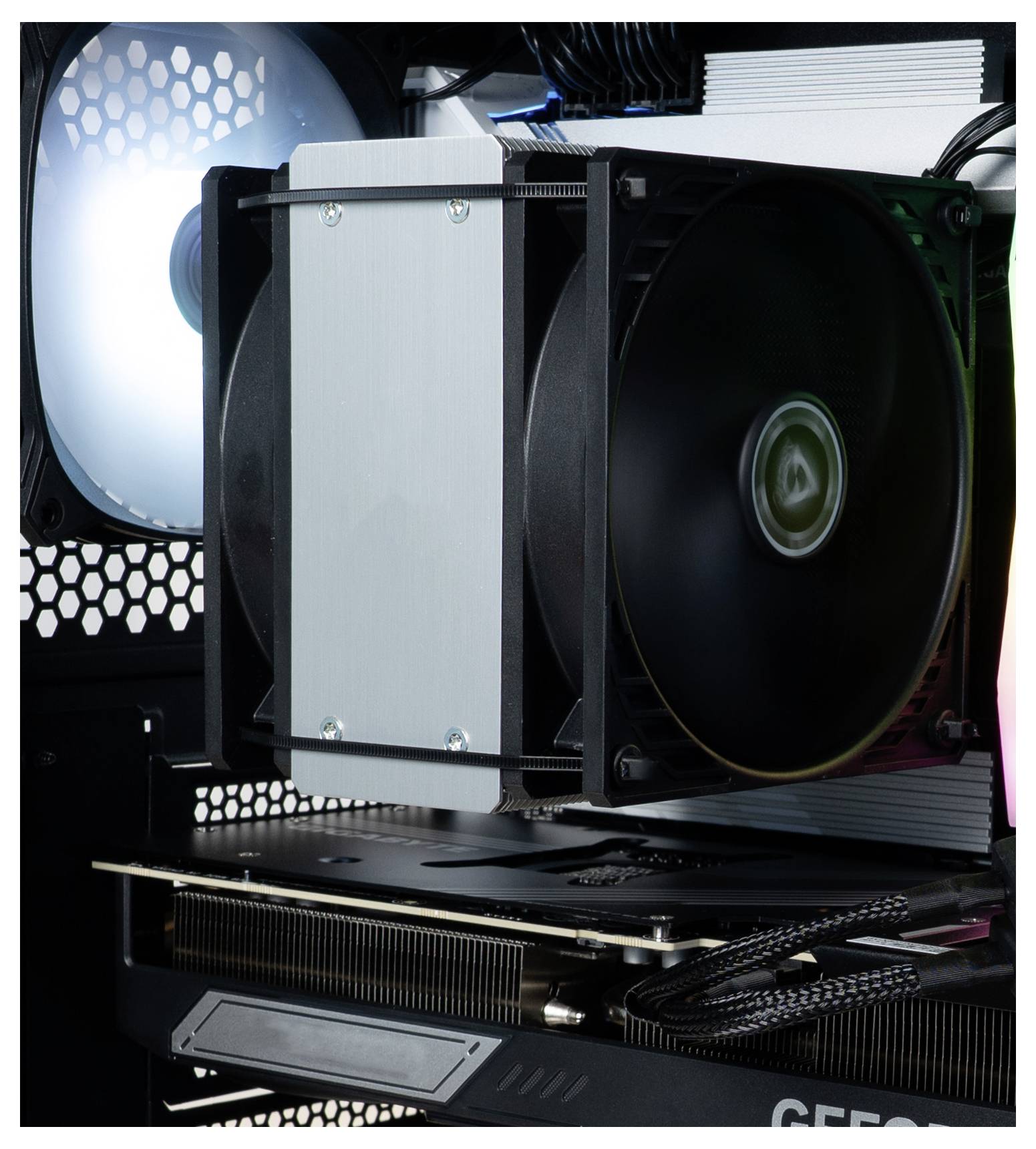 Das Innere eines Computergehäuses zeigt einen großen schwarzen Kühlventilator, der an einem Kühlkörper befestigt ist, sowie einen Teil einer Grafikkarte mit sichtbarer Schaltkreisstruktur.