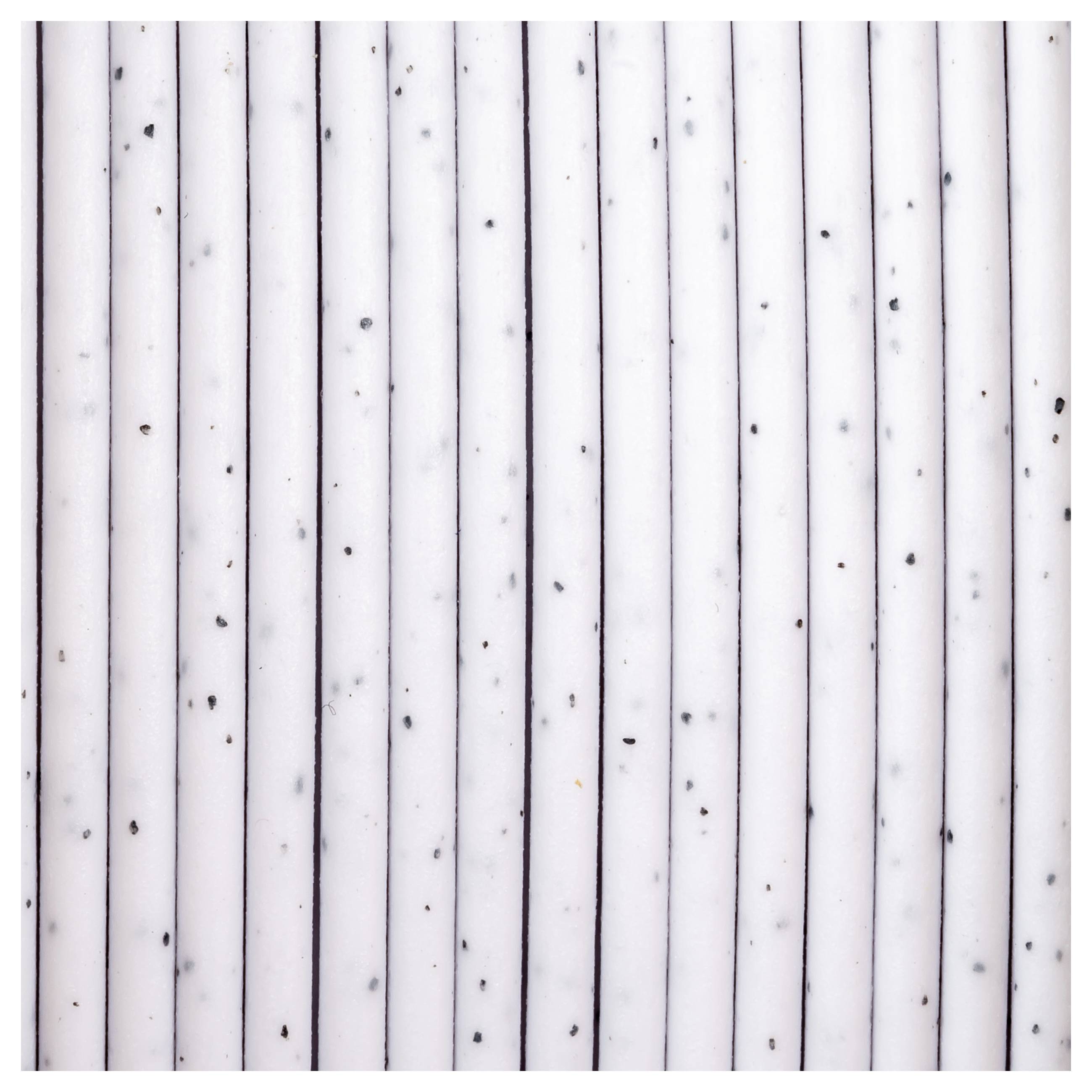 Einige weiße Stangen mit schwarzen Punkten, gleichmäßig nebeneinander liegend auf einer hellen Oberfläche, bilden ein geometrisches Muster.